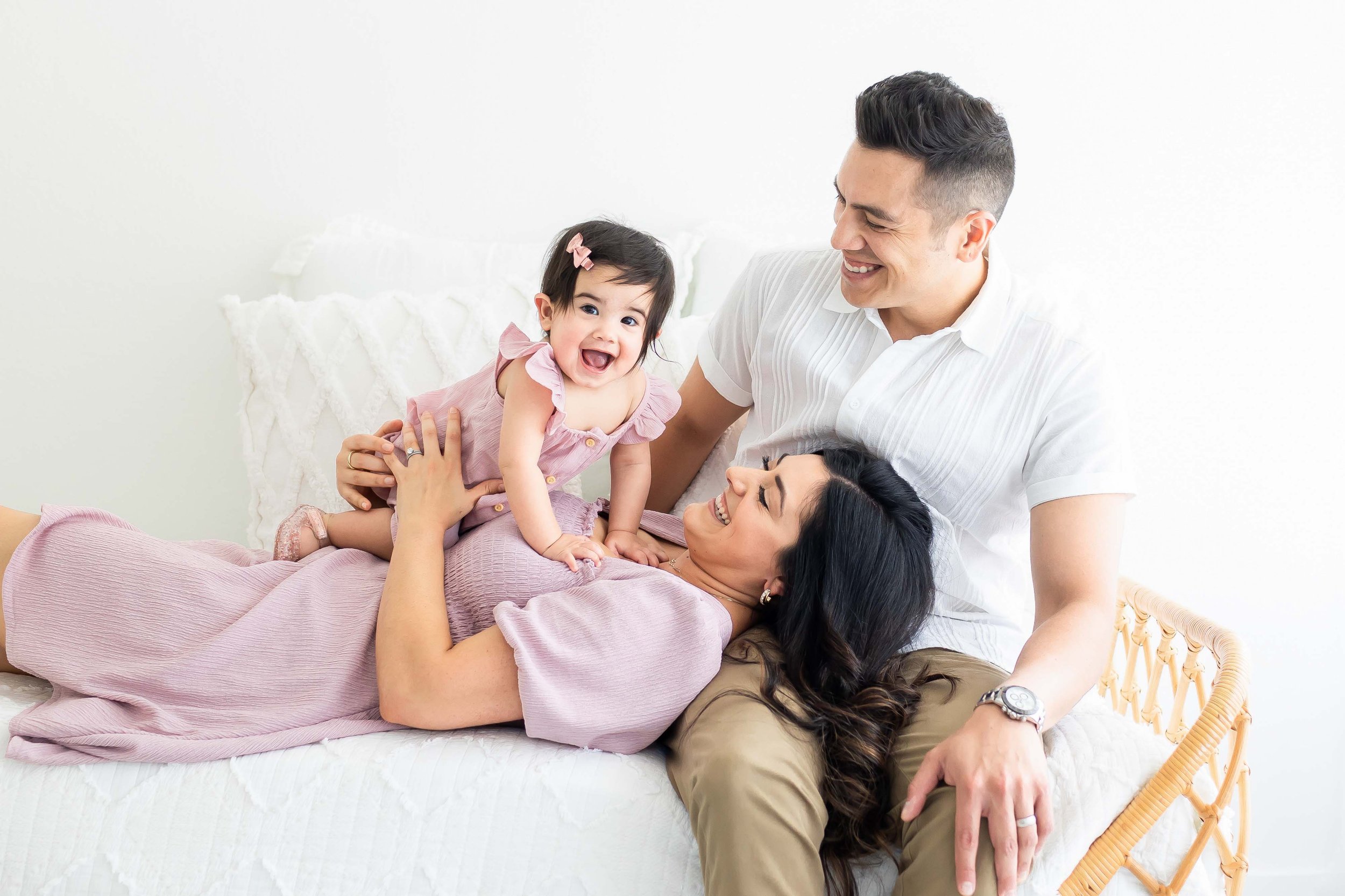 Family of four enjoying playful moment on bed,  at East and Elm Portrait Studio during an in-studio family photography session in Fairport, NY.