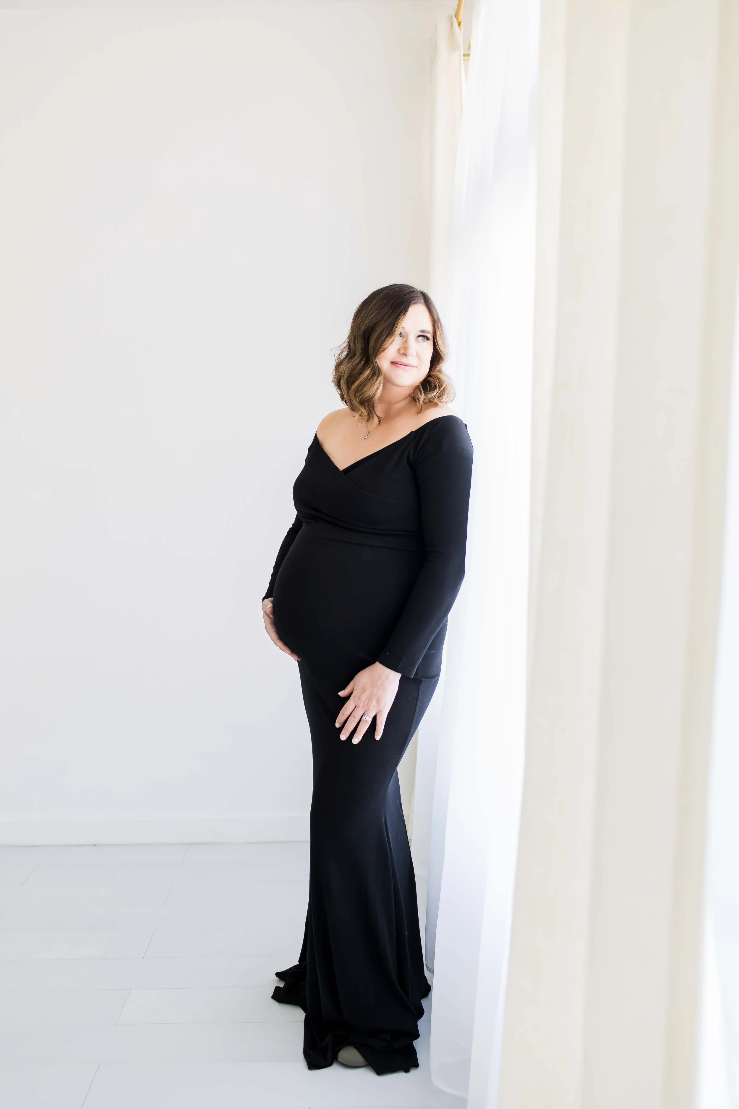 pregnant mom wearing black at East and Elm Portrait Studio in Fairport, NY during maternity session