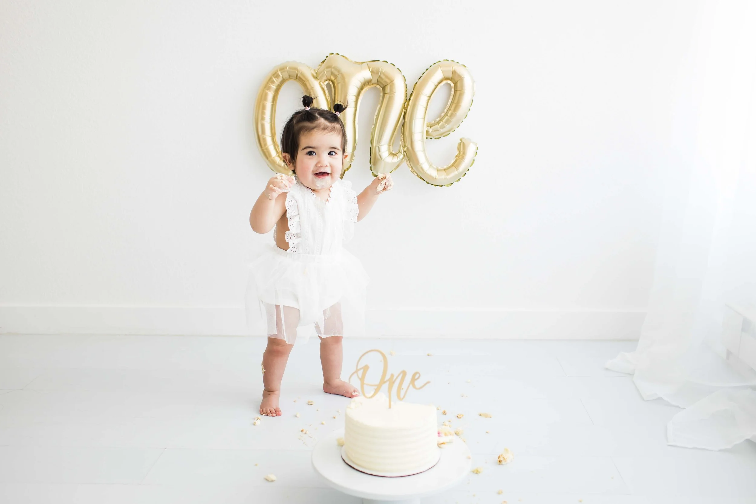 Toddler girl celebrating her first birthday with 0 and 1 balloons and a smash cake, Rochester NY first birthday photography