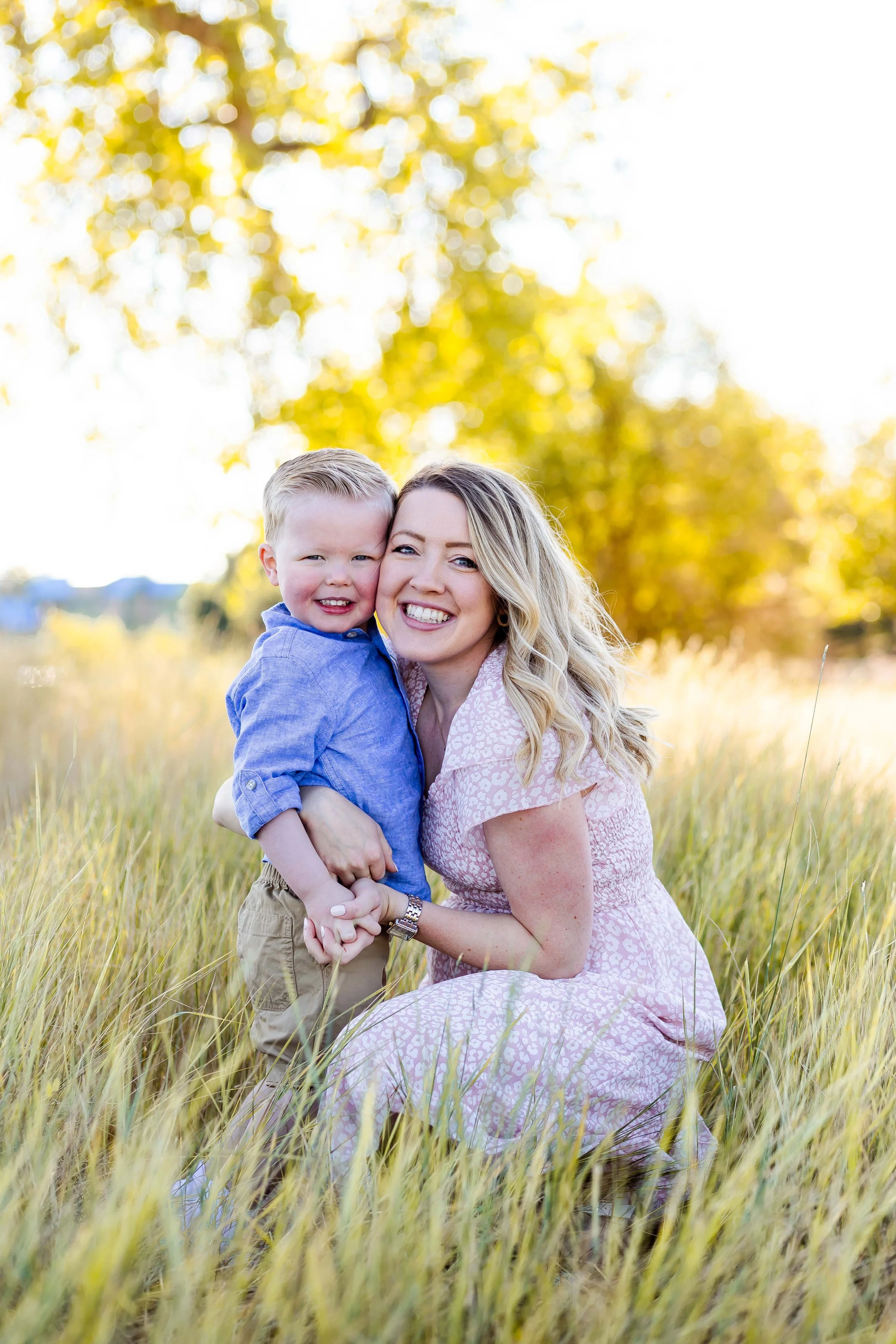 A  mom smiling and holding her son at an outdoor family session with East and Elm Portrait studio in Rochester, NY.
