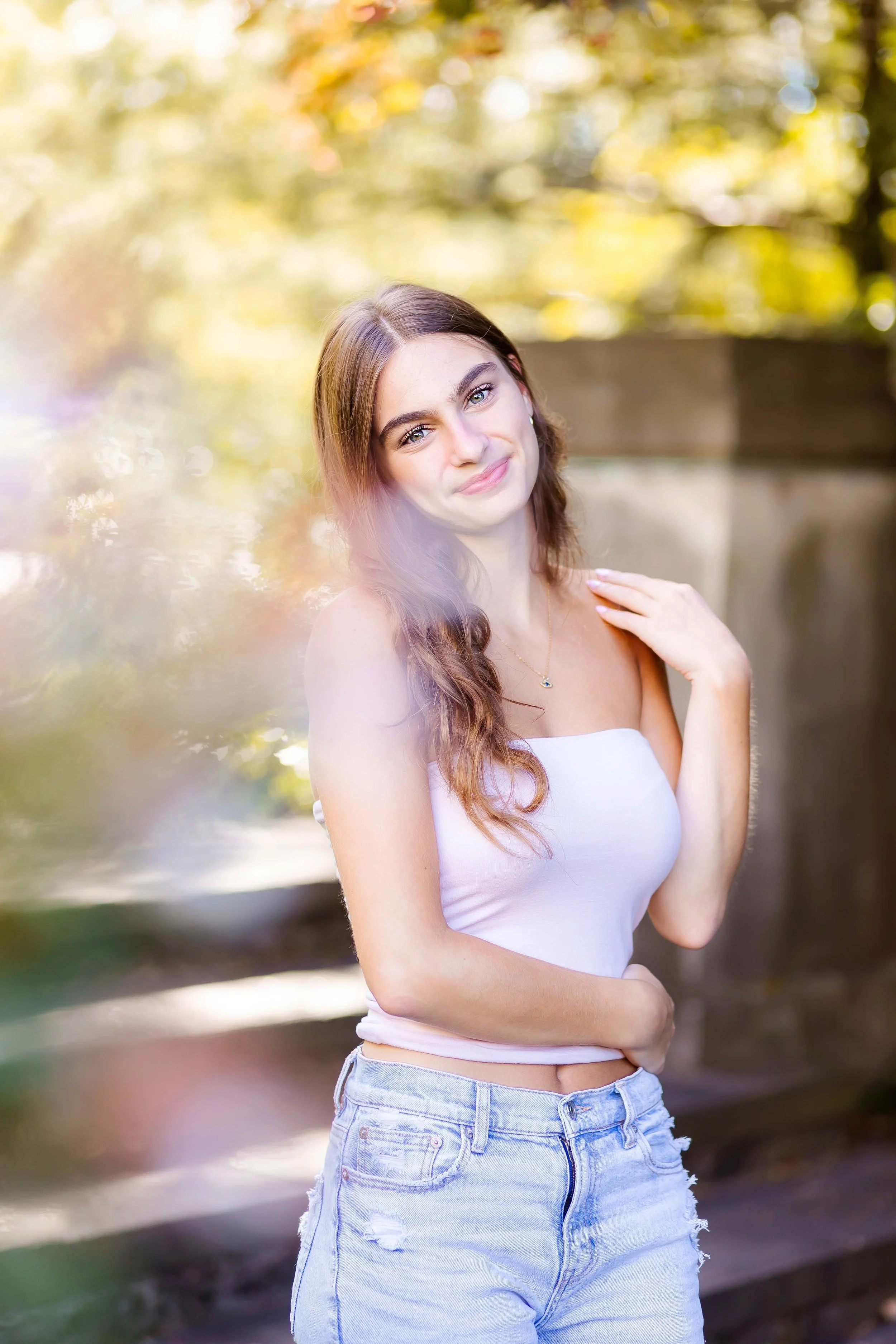 A senior girl smiling outdoors during her senior portrait session with East and Elm Portrait Studio in Rochester, NY.