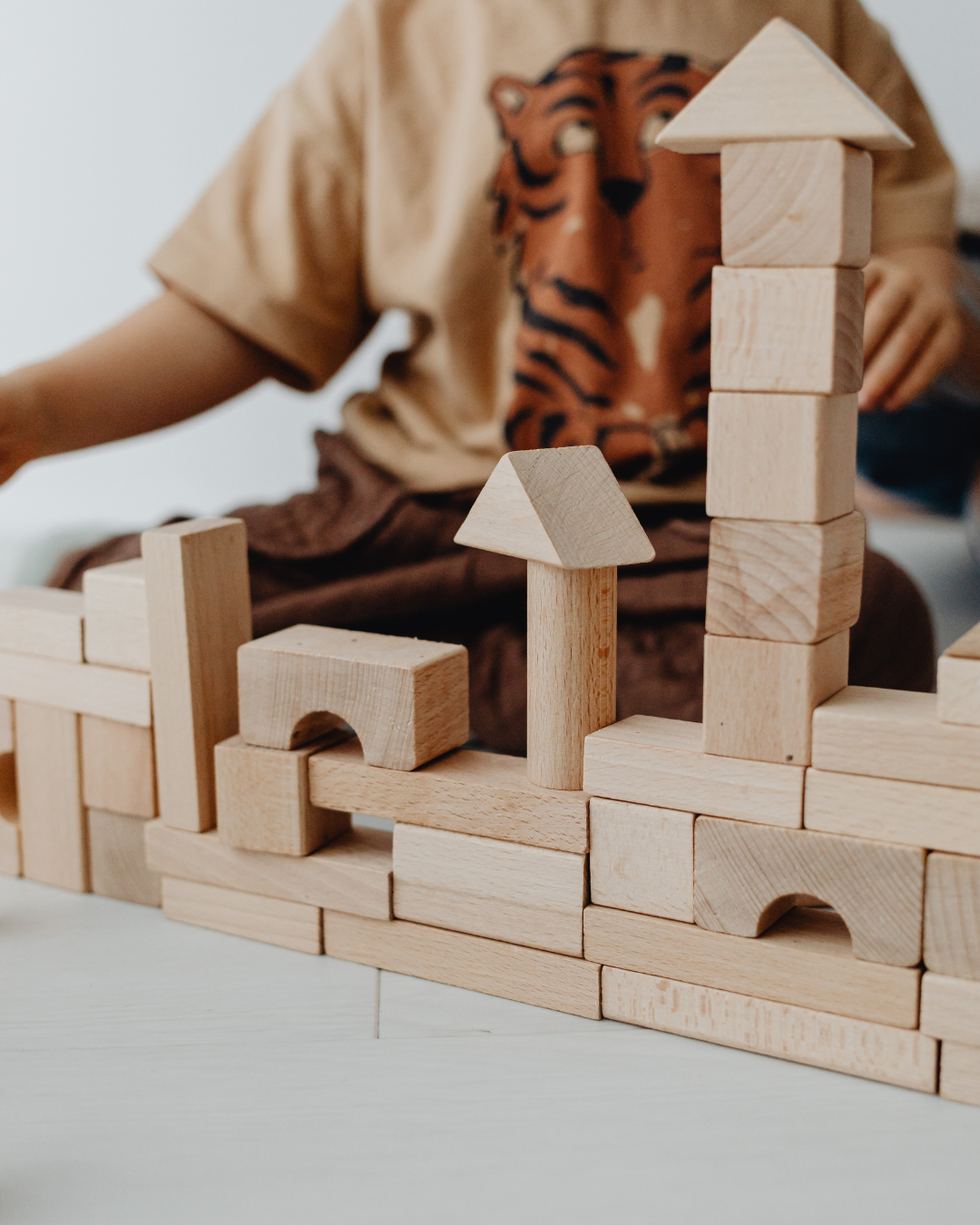 Child playing with wooden building blocks, stacking them into towers and structures.