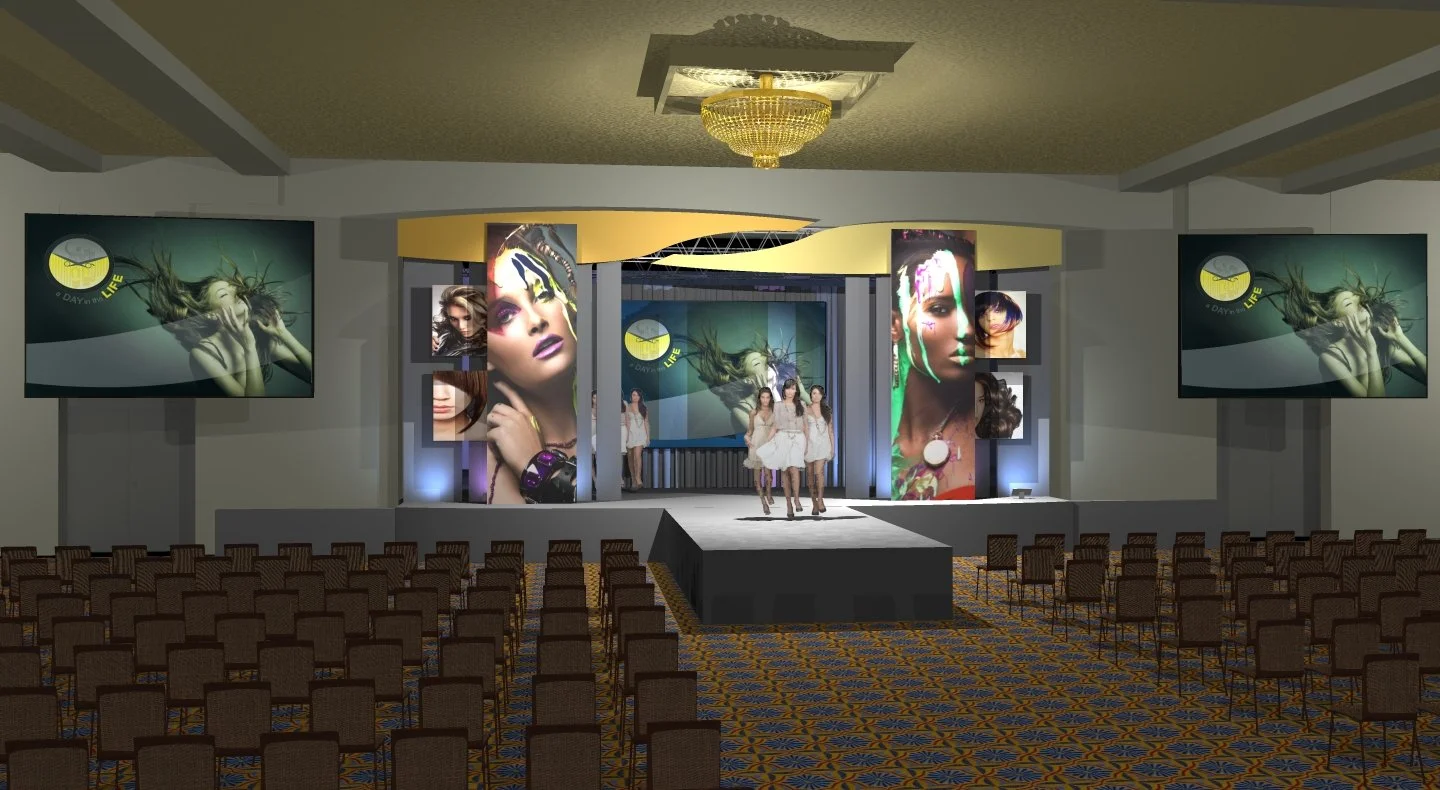 An empty event hall with a stage, four models walking towards the stage, large screens showing a model with colorful makeup, and smaller screens with similar images. The hall has patterned carpet, rows of chairs, and a chandelier on the ceiling.