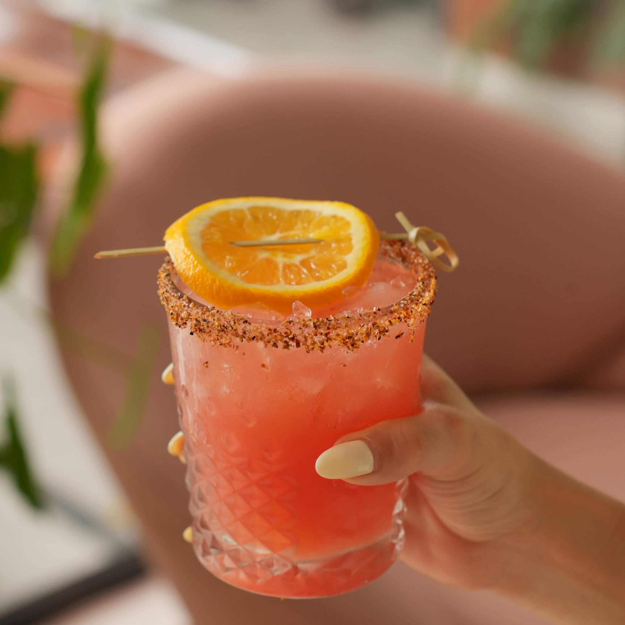 Close-up of a drink glass with a salted rim, garnished with a slice of orange on top of a cocktail.