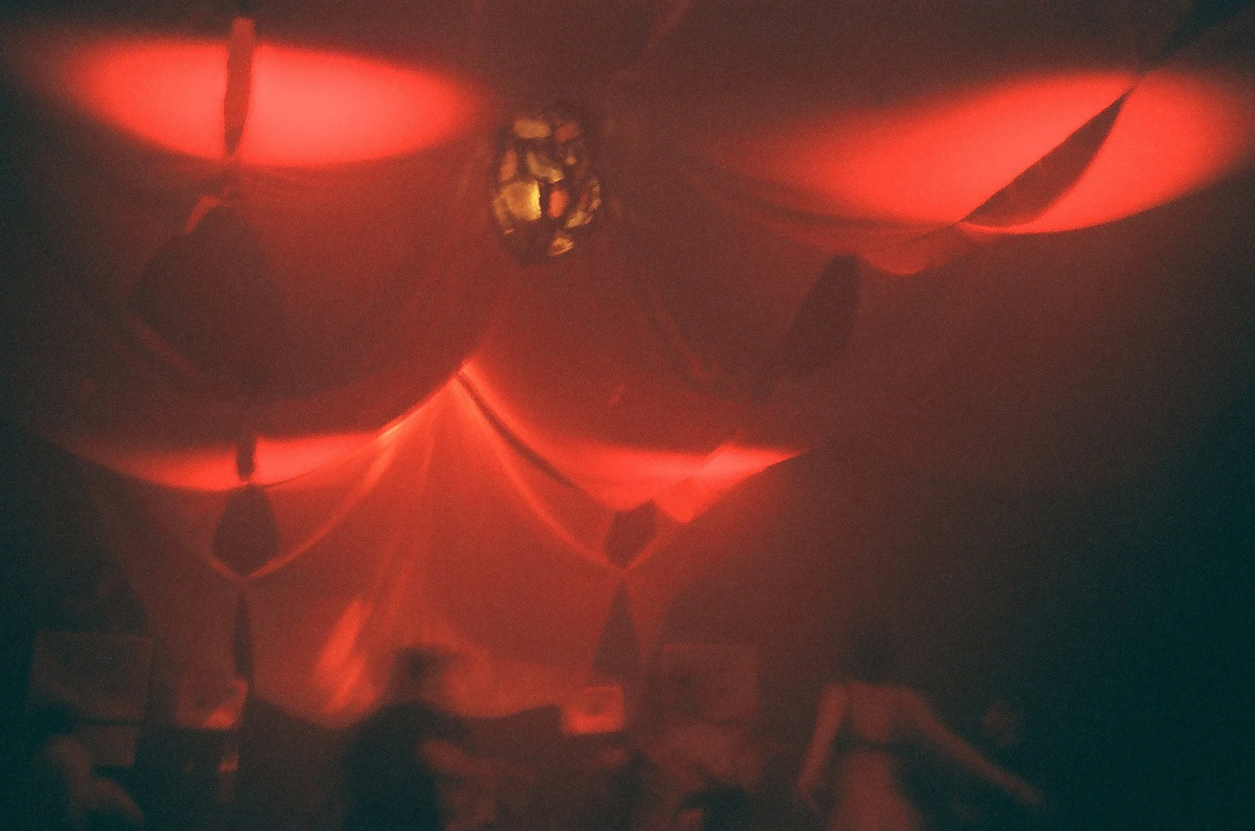 Close-up of a carved pumpkin with red light shining through, highlighting the jagged eyes and mouth.