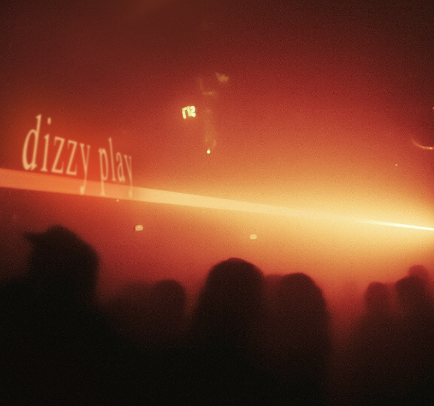 A red-lit nightclub scene with silhouettes of people, a laser light, and the words 'dizzy play' on a wall.