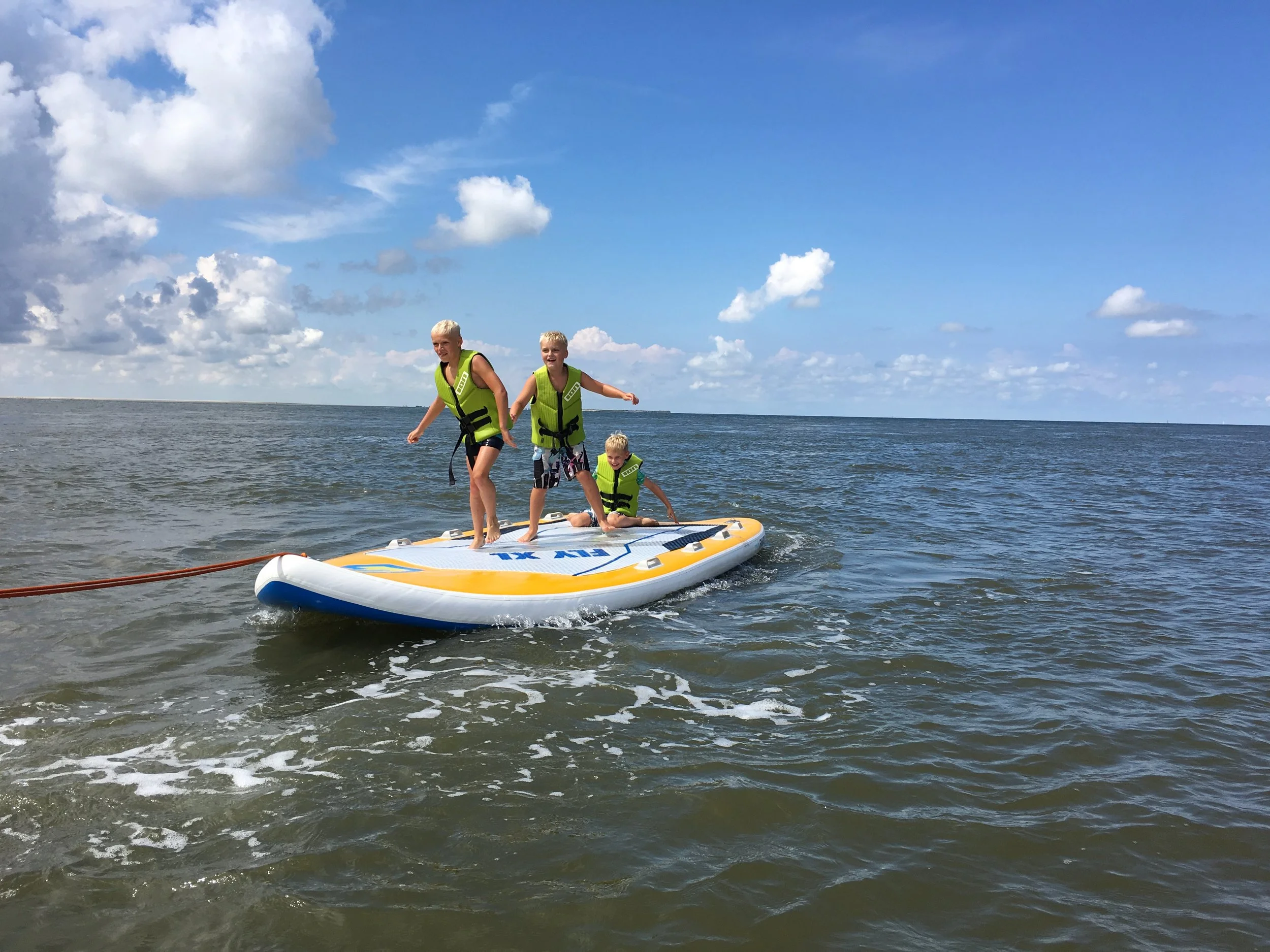 Kinderen op een bananenboot in zee bij Ameland