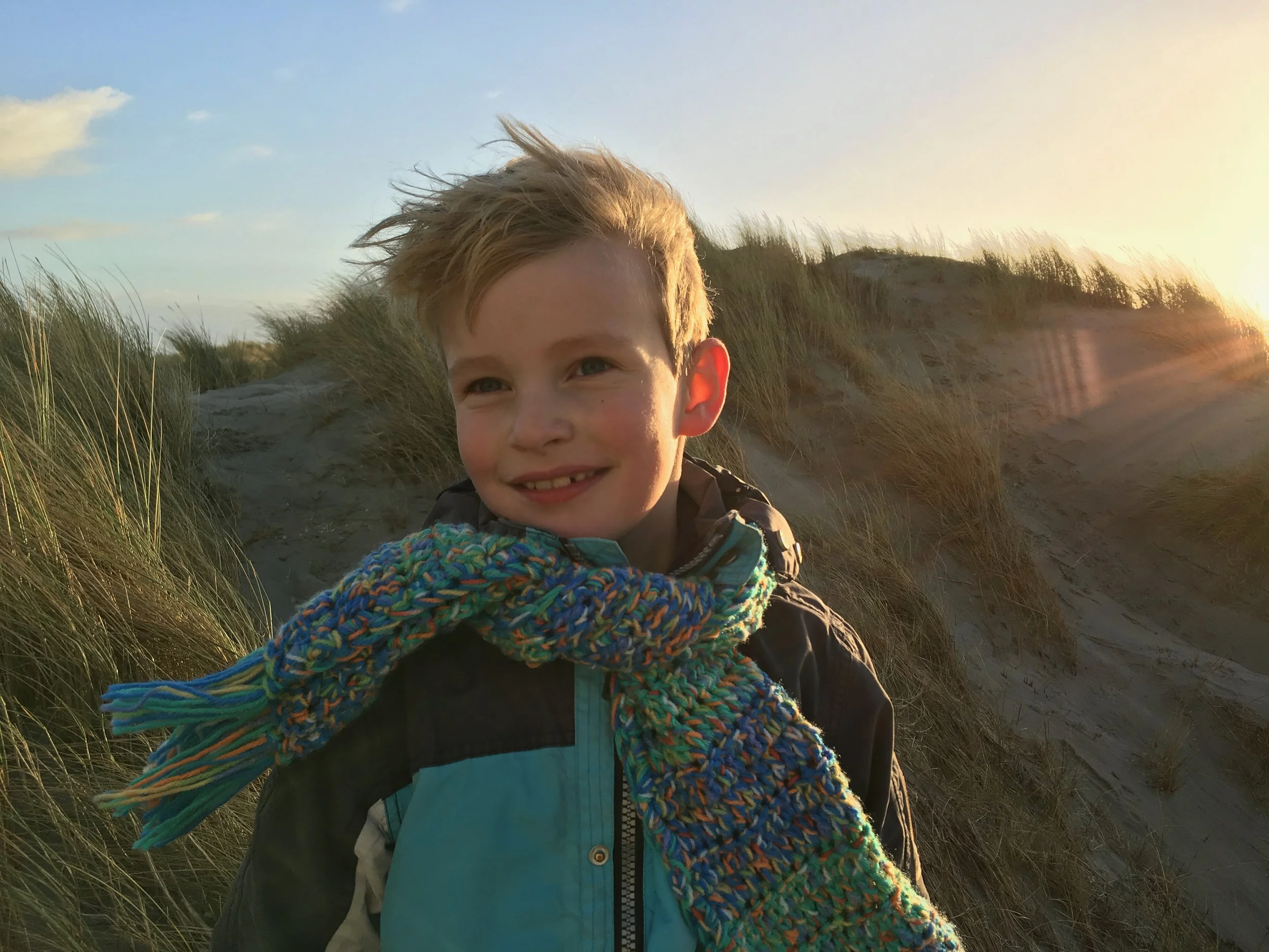 Jongen met sjaal in de duinen van Ameland bij avondlicht