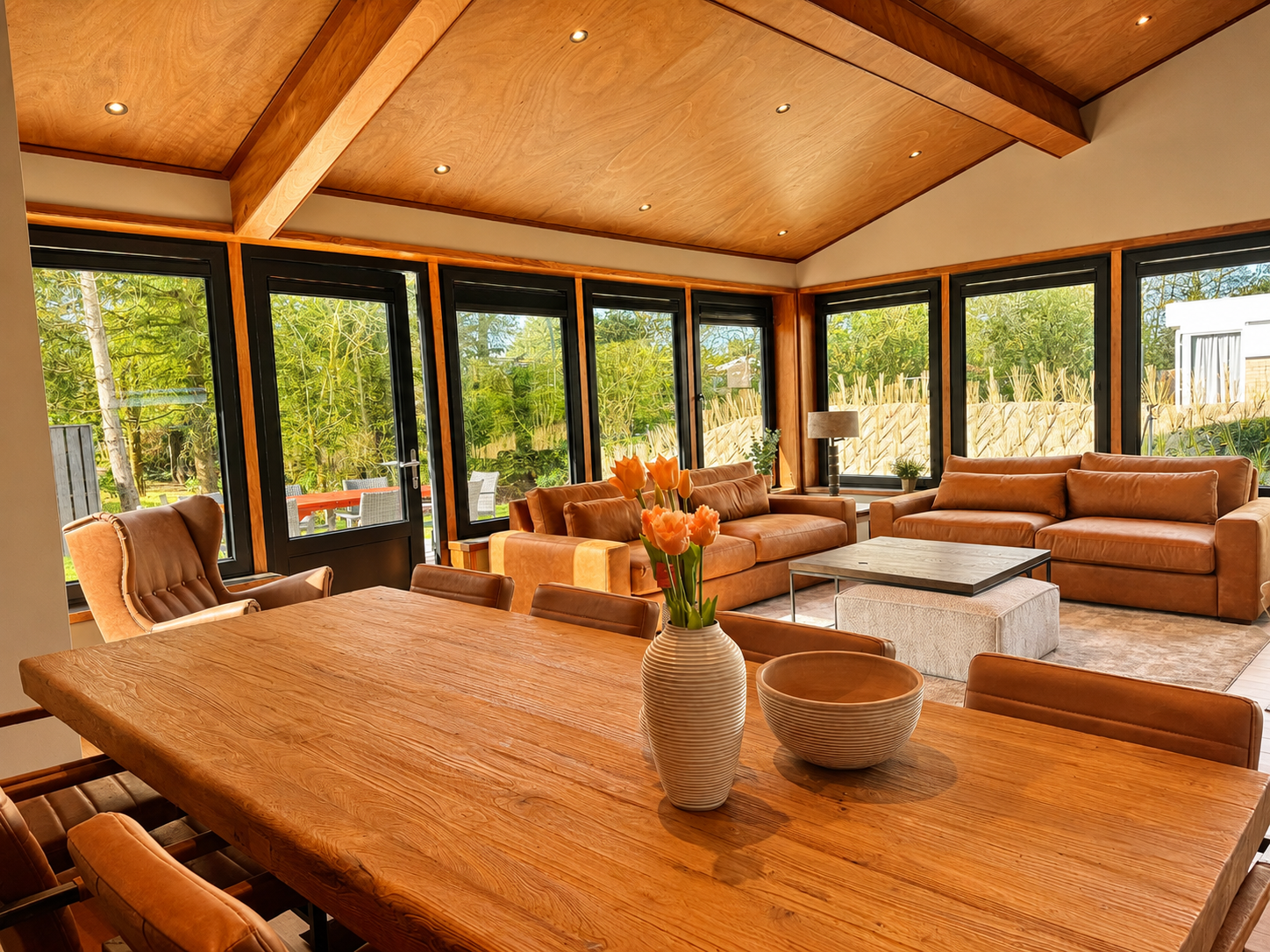 Open woonkamer met lange eettafel en uitzicht op de tuin in Villa Duikenburg in Ballum op Ameland