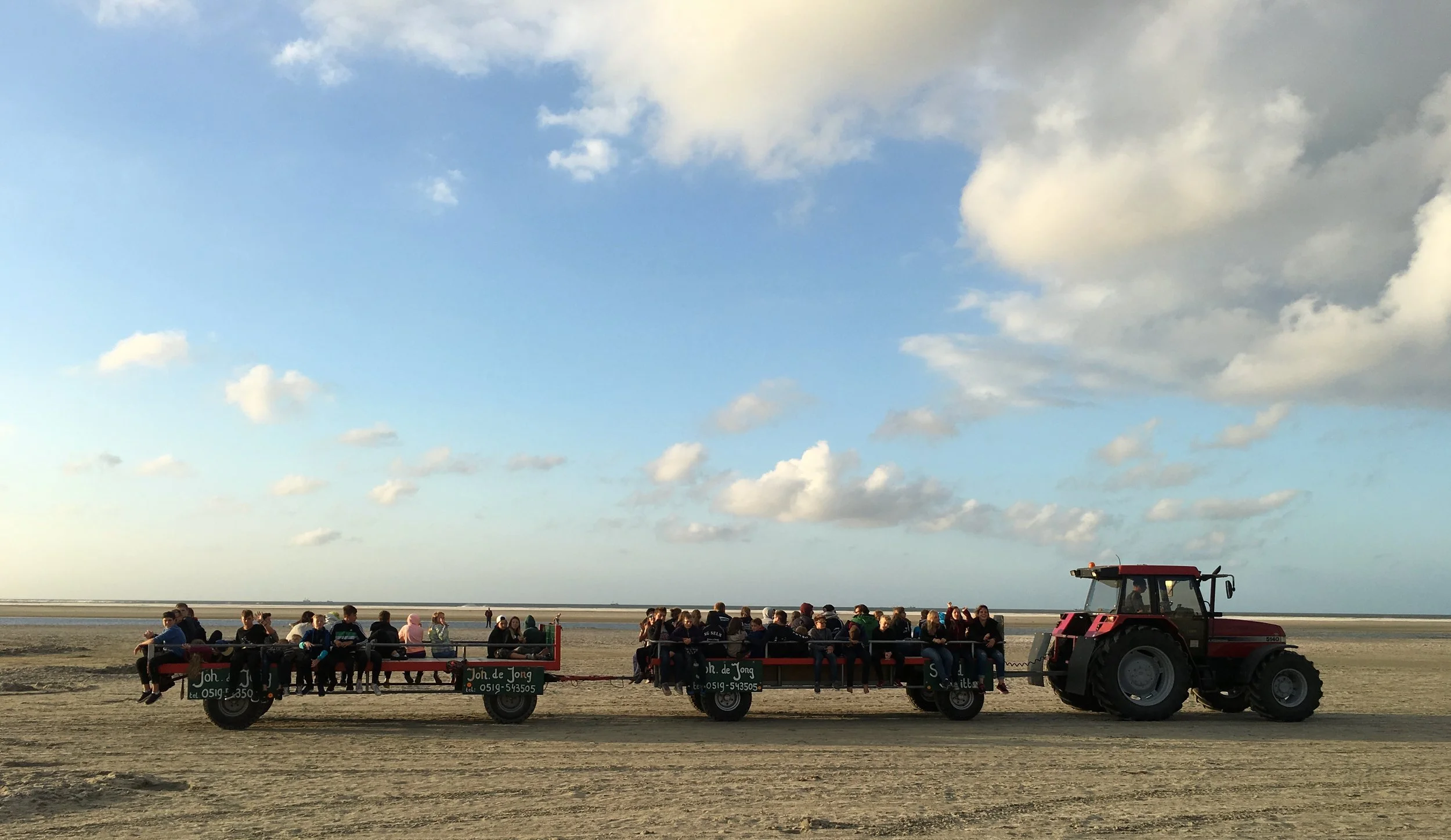 Tractoren met wagens vol mensen op het strand van Ameland bij avondlicht
