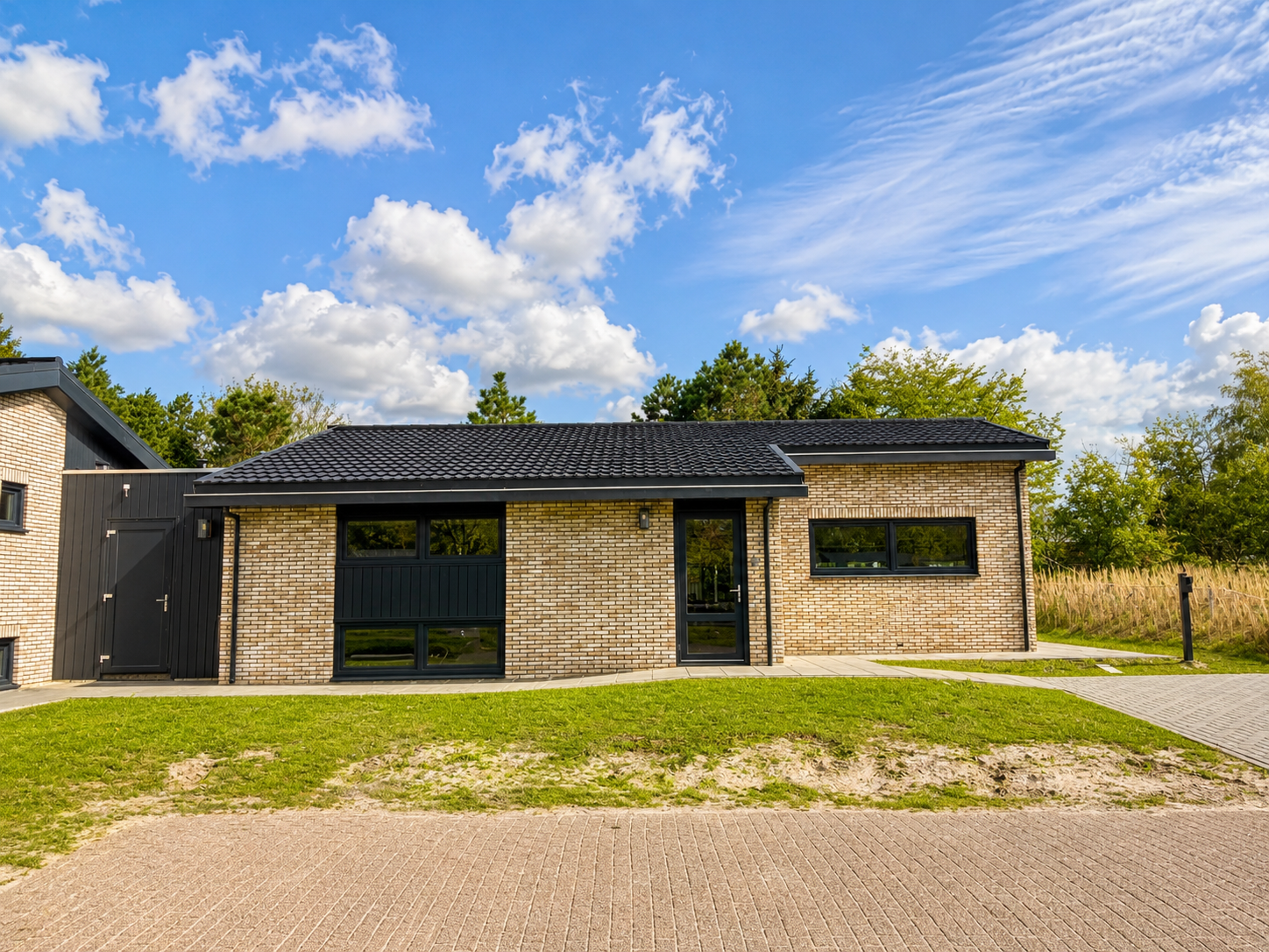 Voorgevel van Villa Duikenburg met grote ramen en gazon in Ballum op Ameland
