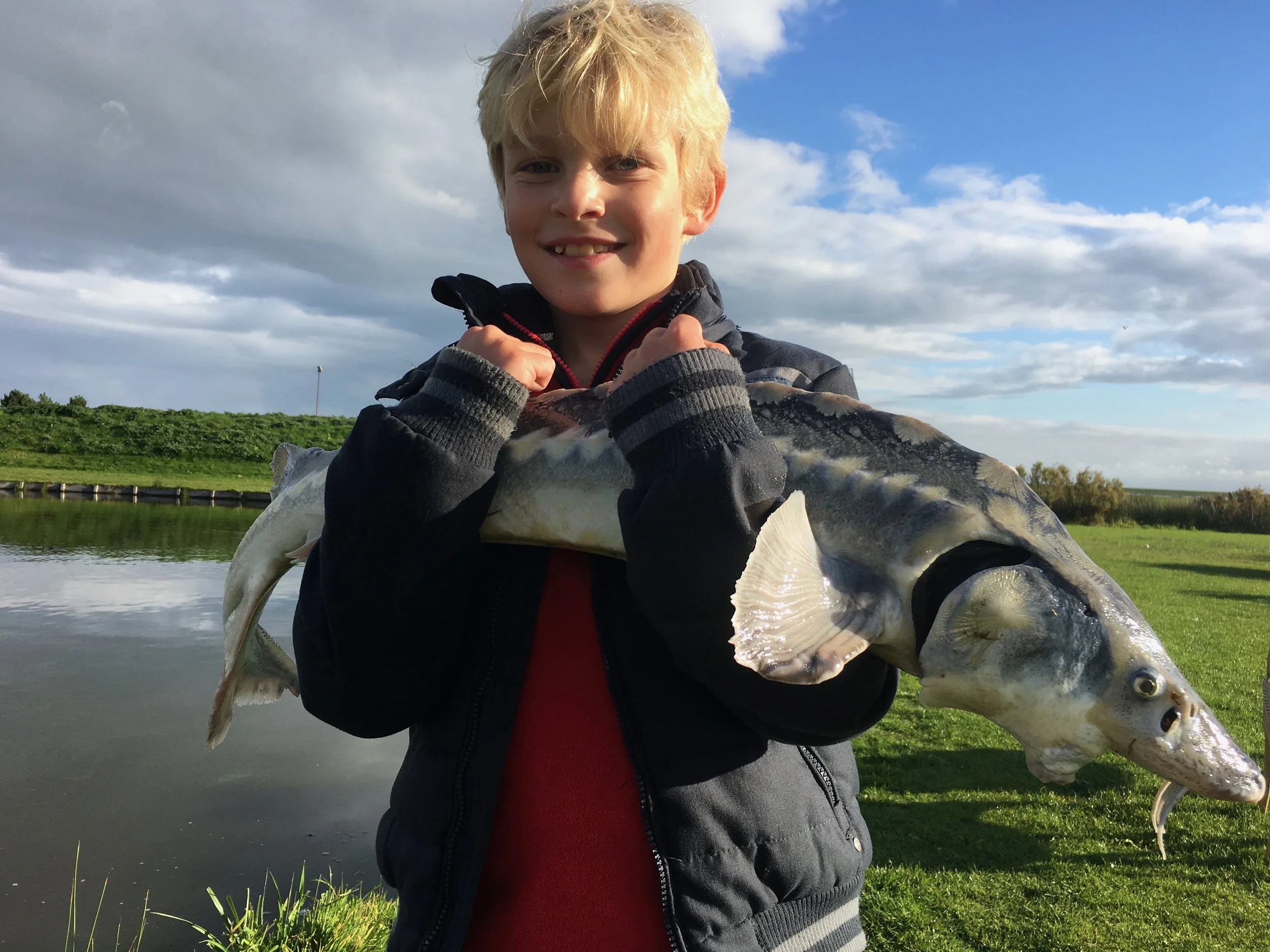 Jongen toont een gevangen vis aan de waterkant op Ameland