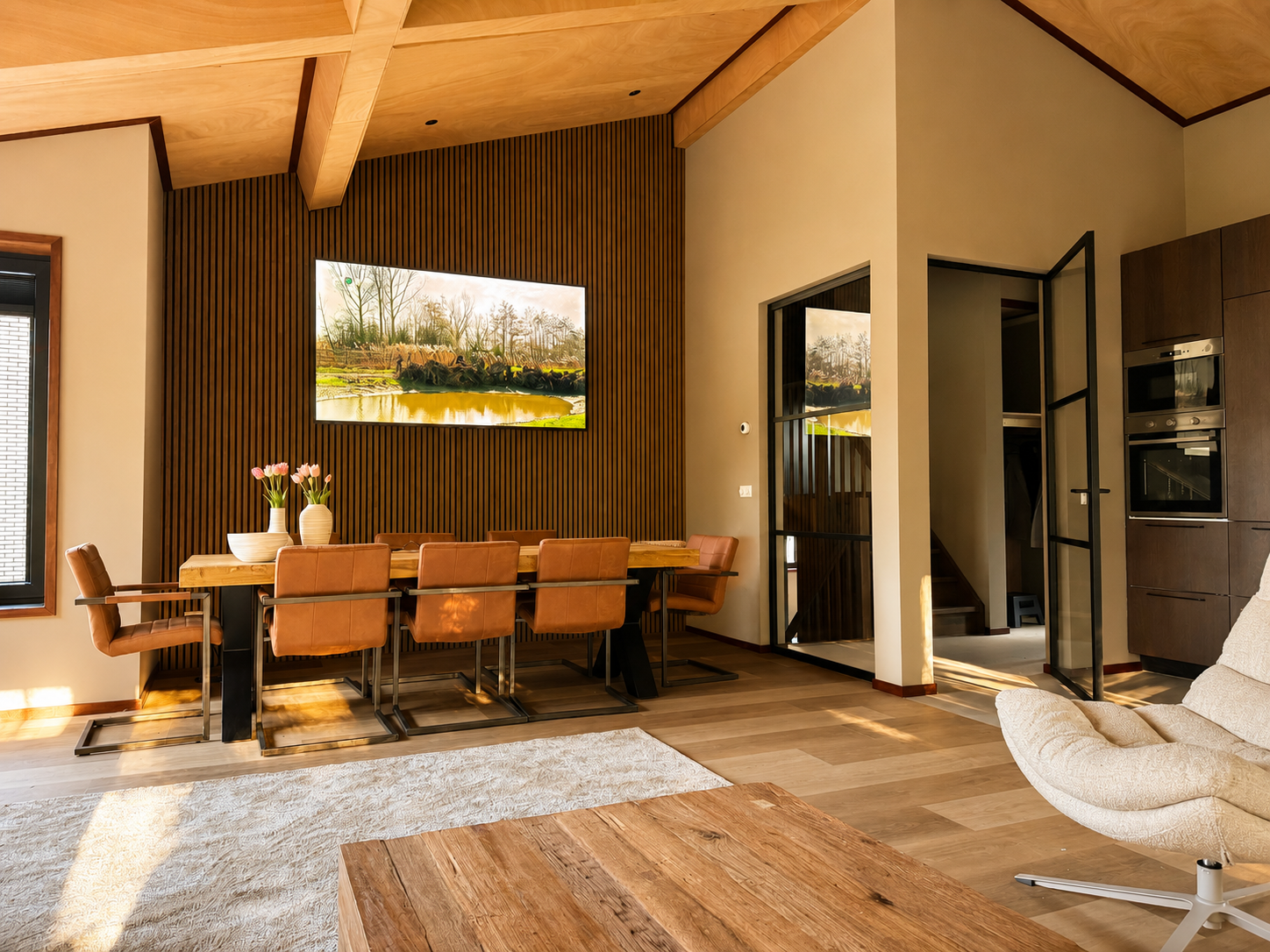 Woonkamer met eettafel, open keuken en houten plafond in Villa Oostermeer in Ballum op Ameland