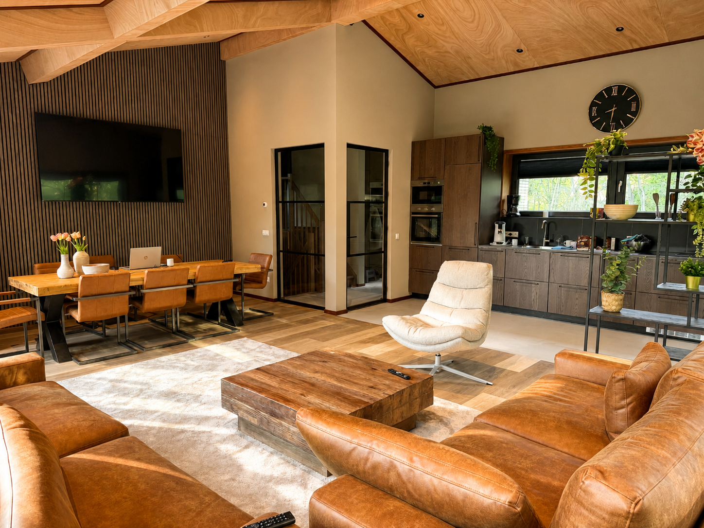 Woonkamer met open keuken, leren bank en eettafel in Villa Oostermeer in Ballum op Ameland