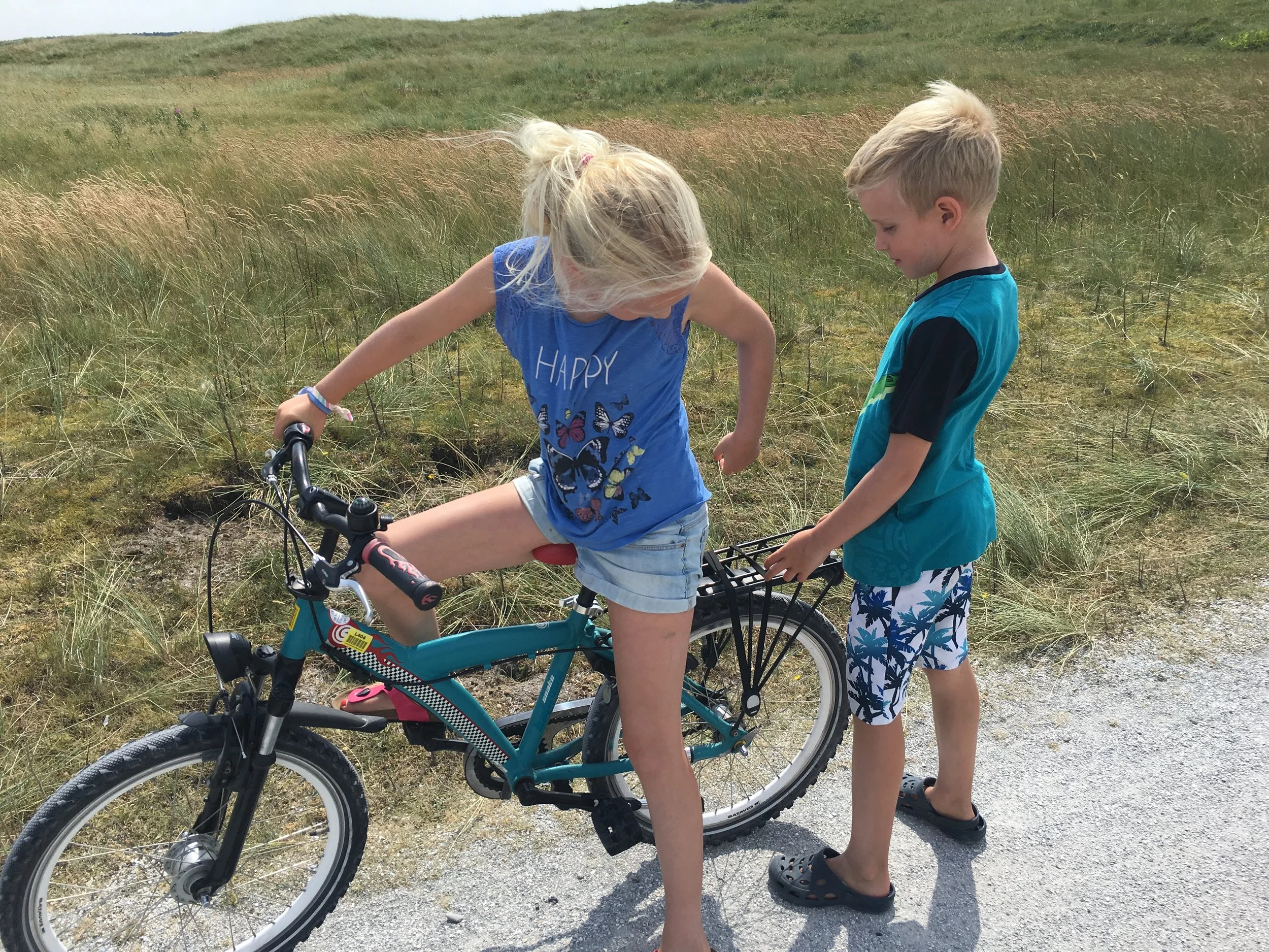 Twee kinderen met een fiets op een duinpad op Ameland