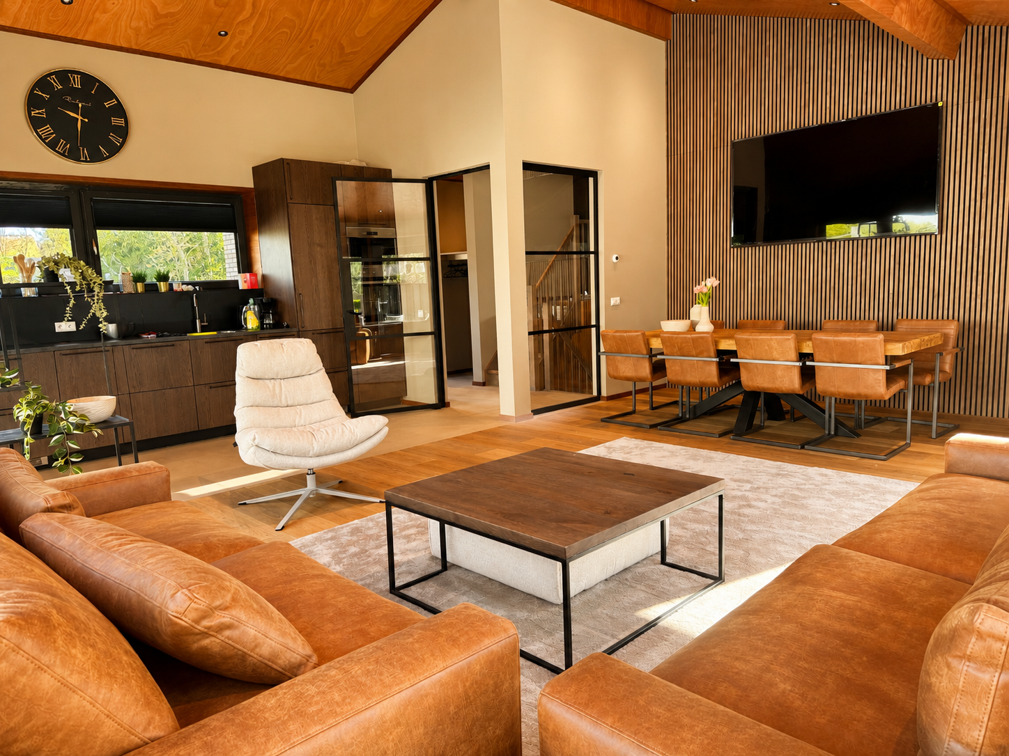 Woonkamer met leren zithoek en houten eettafel in Villa Duikenburg in Ballum op Ameland
