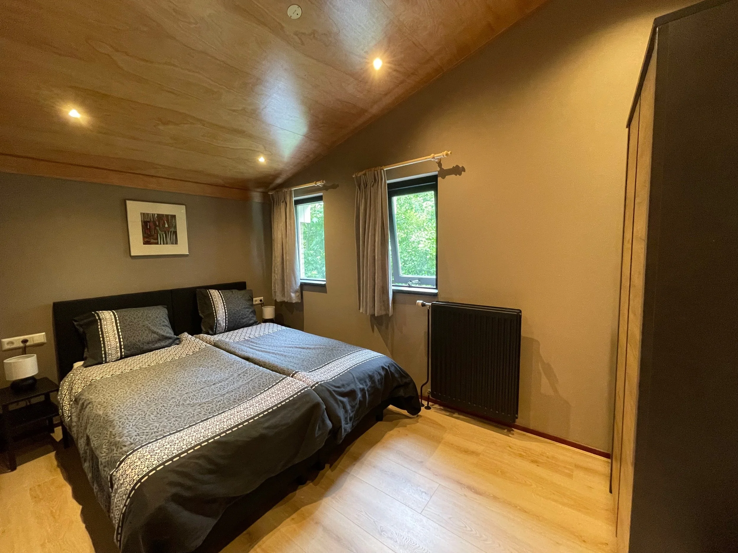 Slaapkamer met tweepersoonsbed en houten plafond in Bungalow Sonnevanck in Ballum op Ameland