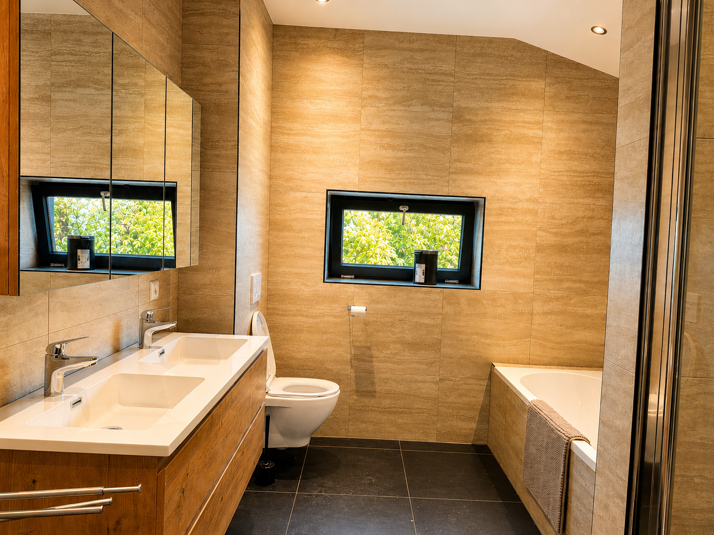 Badkamer boven met dubbele wastafel, ligbad en toilet in Villa Oostermeer in Ballum op Ameland