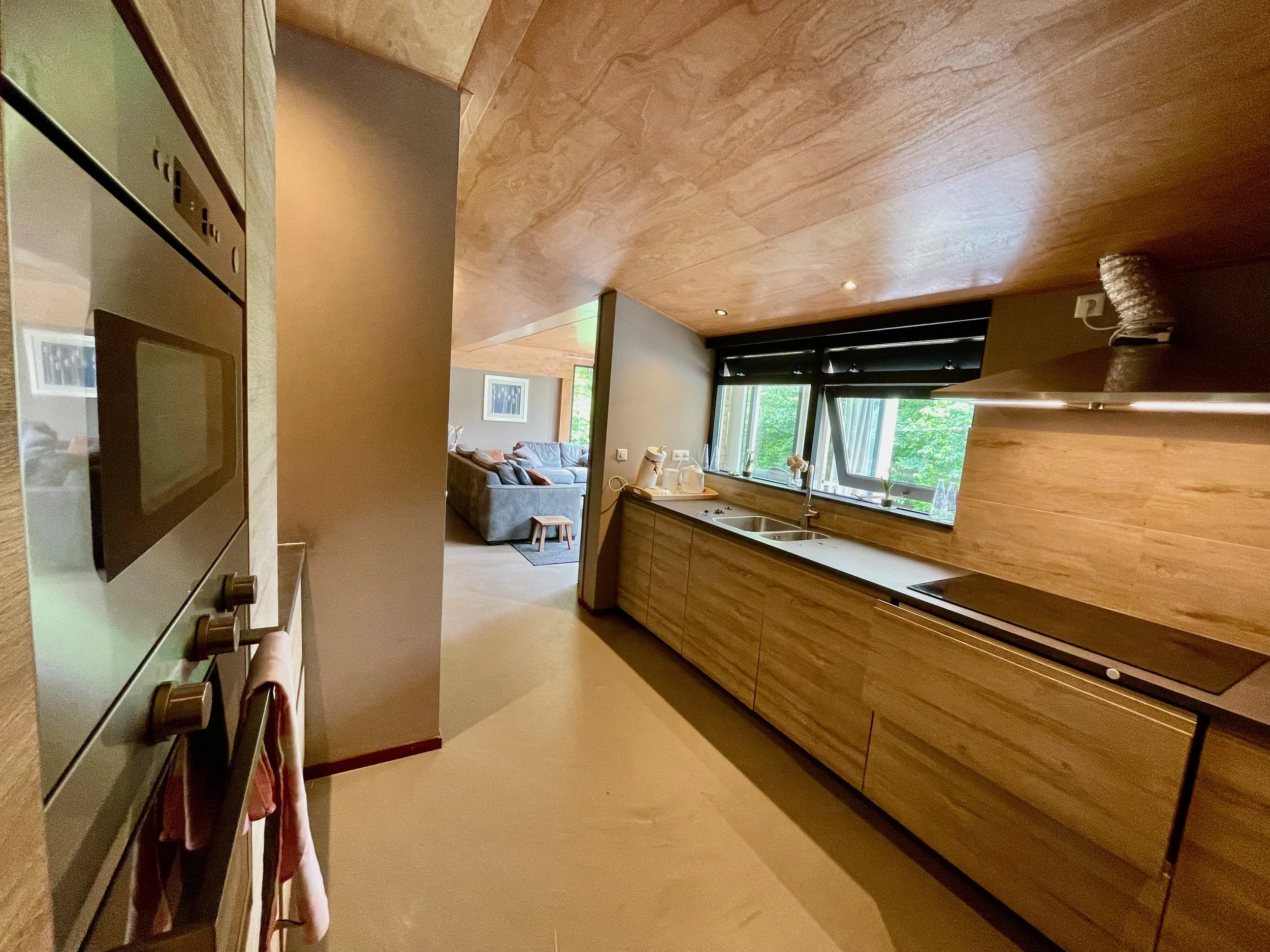 Keuken met houten kasten en doorkijk naar de woonkamer in Bungalow Sonnevanck in Ballum op Ameland