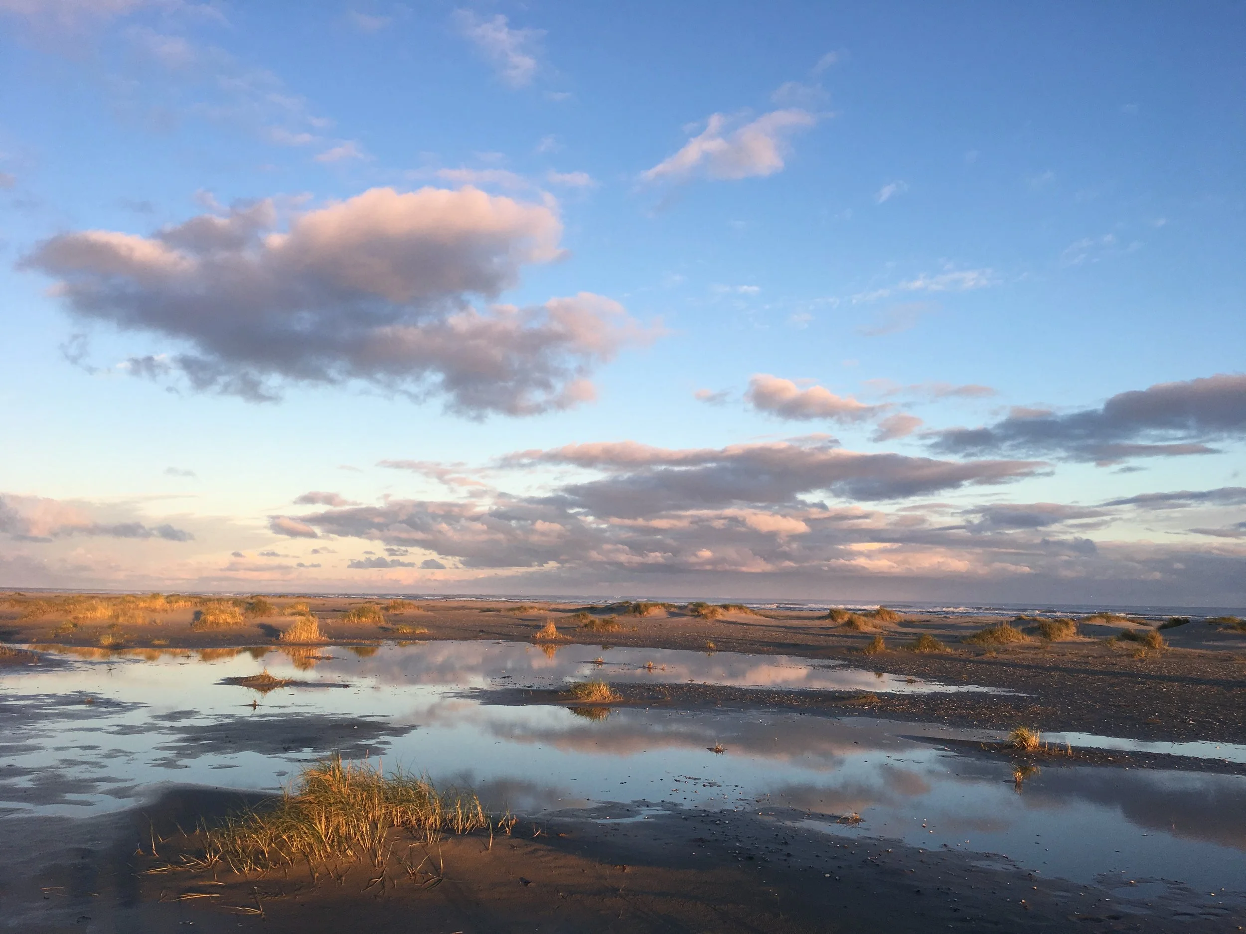 Strand van Ameland bij zonsondergang met spiegelingen in het natte zand