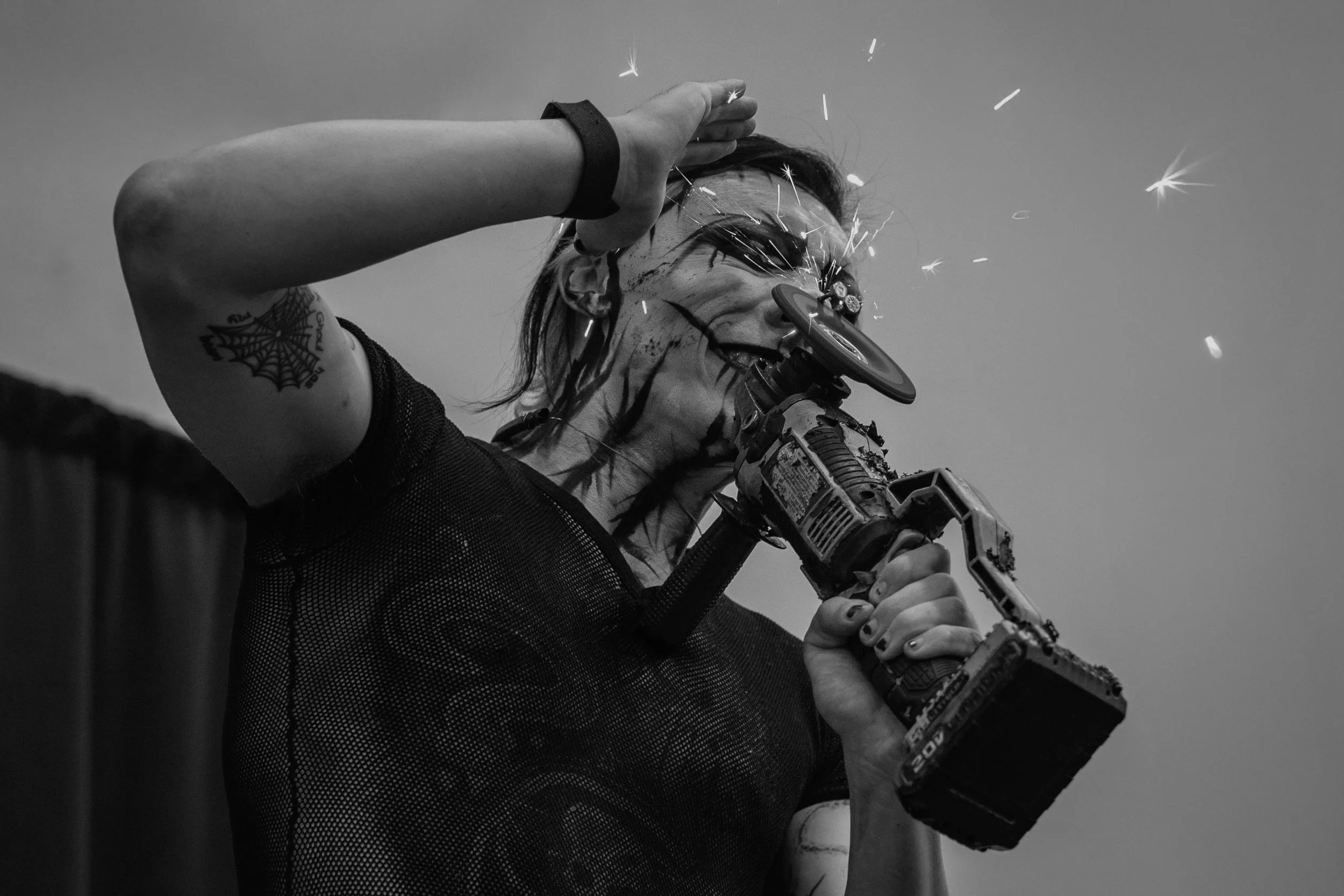 A person holding a sparkler and a power drill, with sparks flying, in black and white.