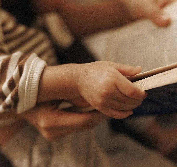 A child wearing a striped long-sleeve shirt holding a book.