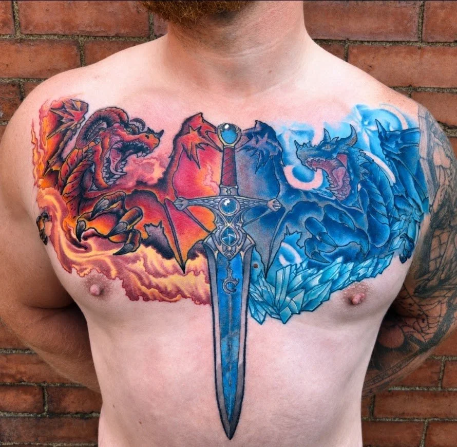 Colorful tattoo of a dragon and a phoenix surrounding a large sword on a man's chest, with a brick wall background.