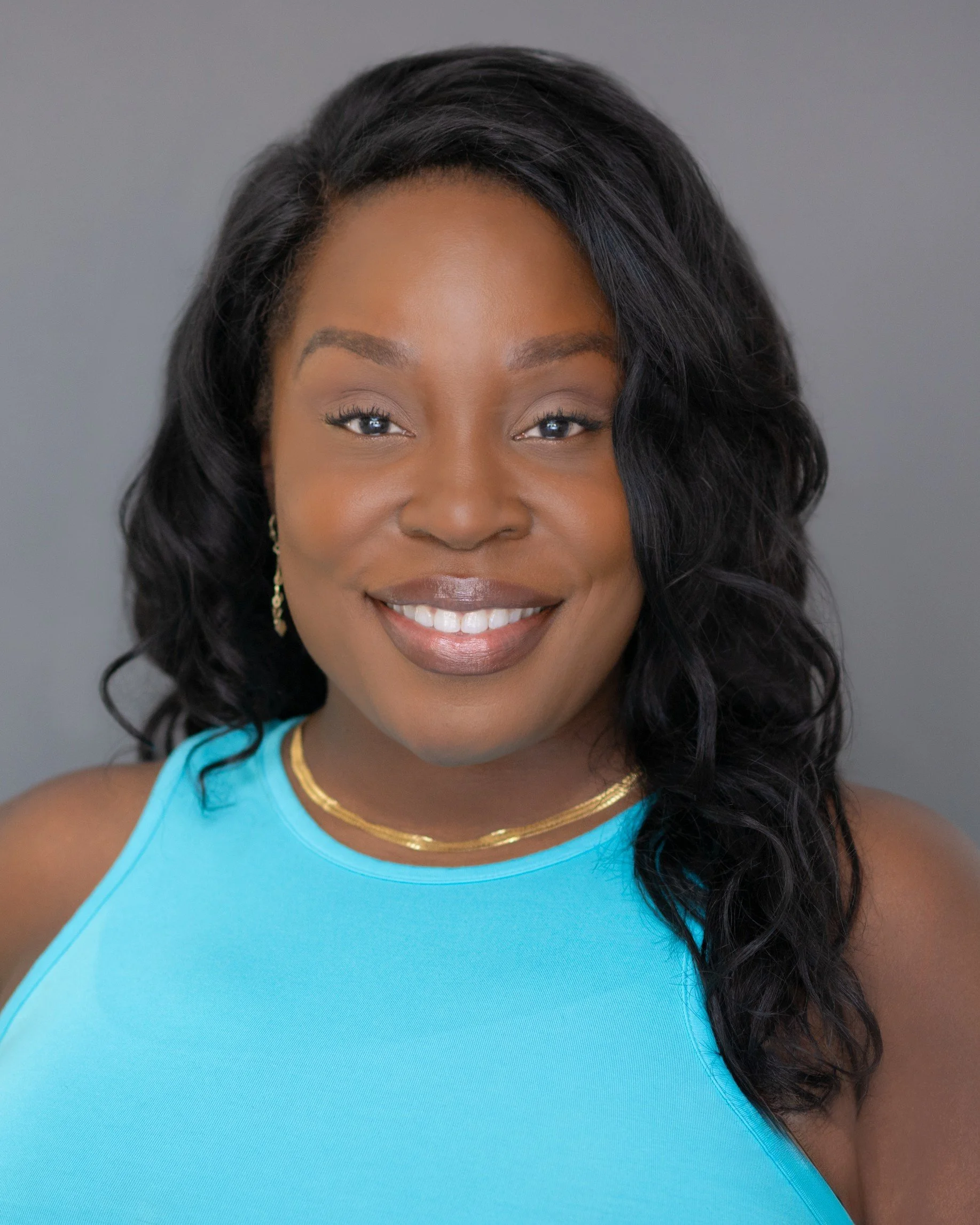 Genesis Beasley, founder of YAAY Studio, smiling against a gray background
