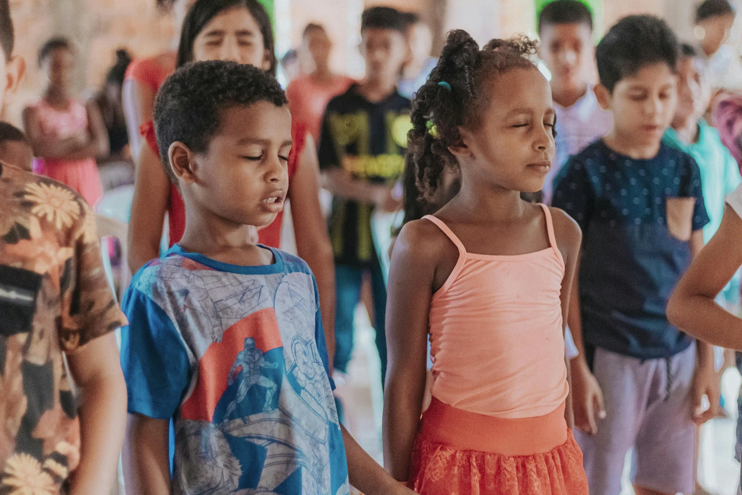Children standing together with their eyes closed during a mindfulness activity
