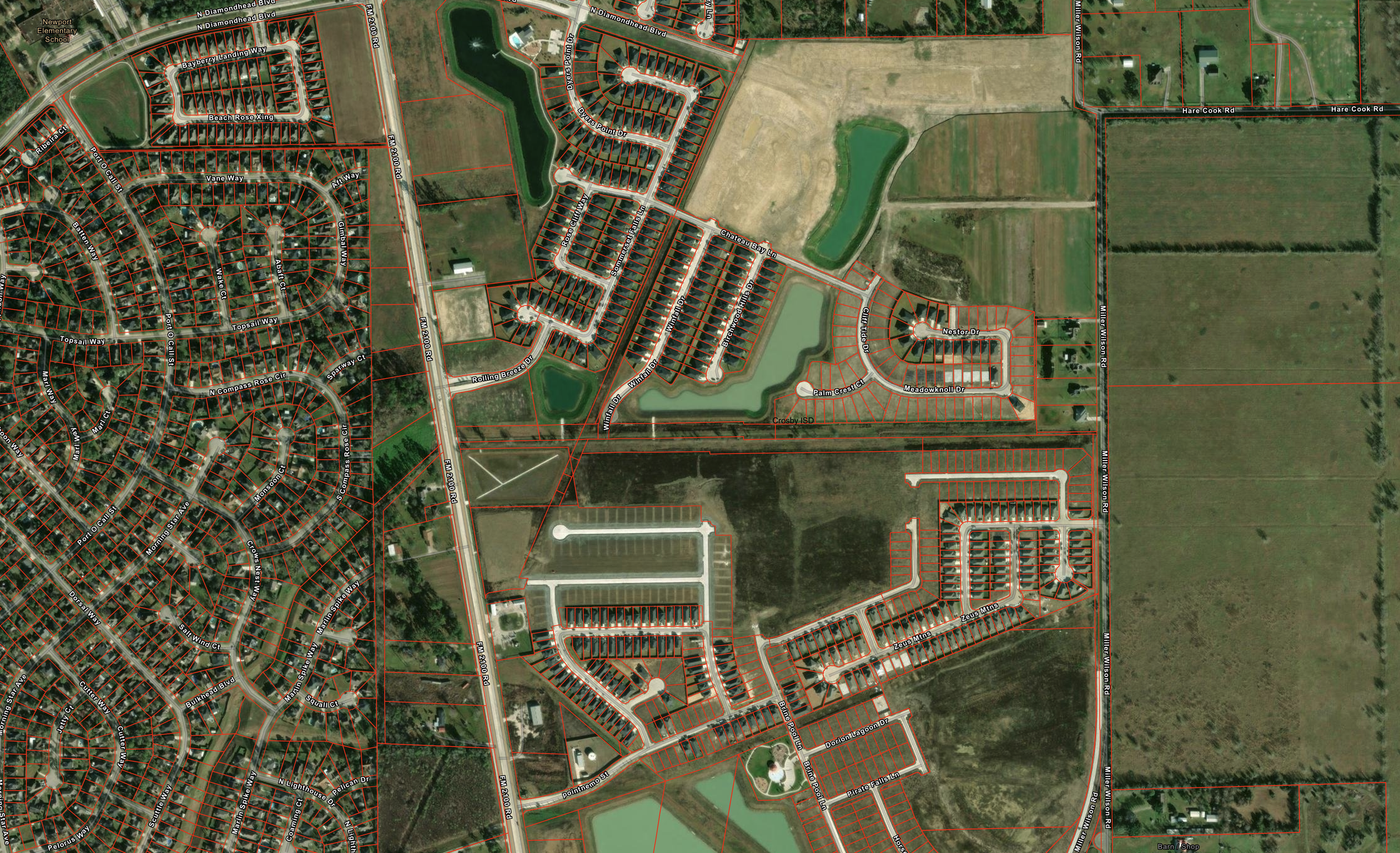 An aerial view of a residential neighborhood with houses, streets, ponds, and open fields, with property boundaries marked in red.