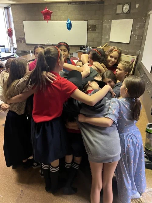 Group of children hugging in a classroom during a Citadel Education Program.