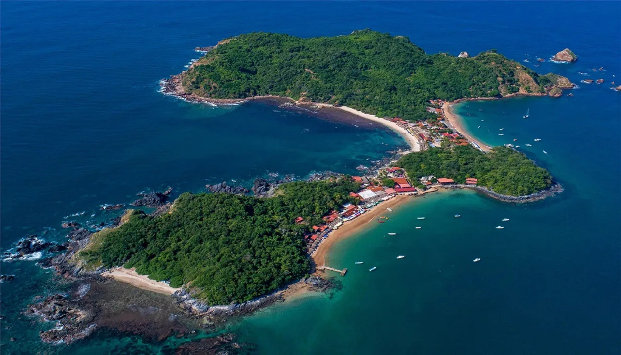 Vista aérea de una isla verde rodeada por el mar, con playas y un pequeño pueblo en la costa.
