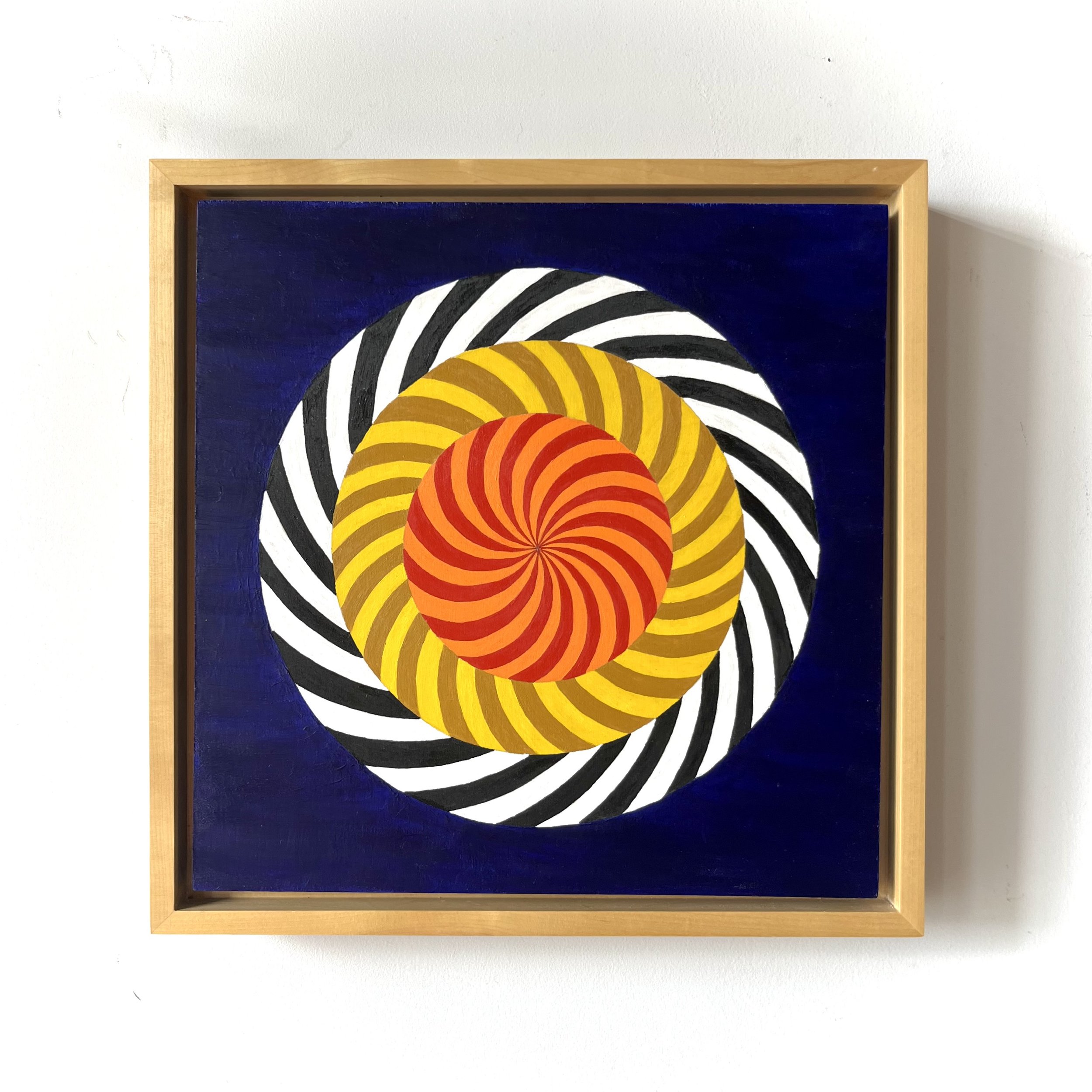 An abstract painting featuring colorful spiral patterns with black and white wavy lines on a dark blue background, framed in light wood.