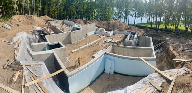 Under construction swimming pool with concrete walls in a backyard during development.
