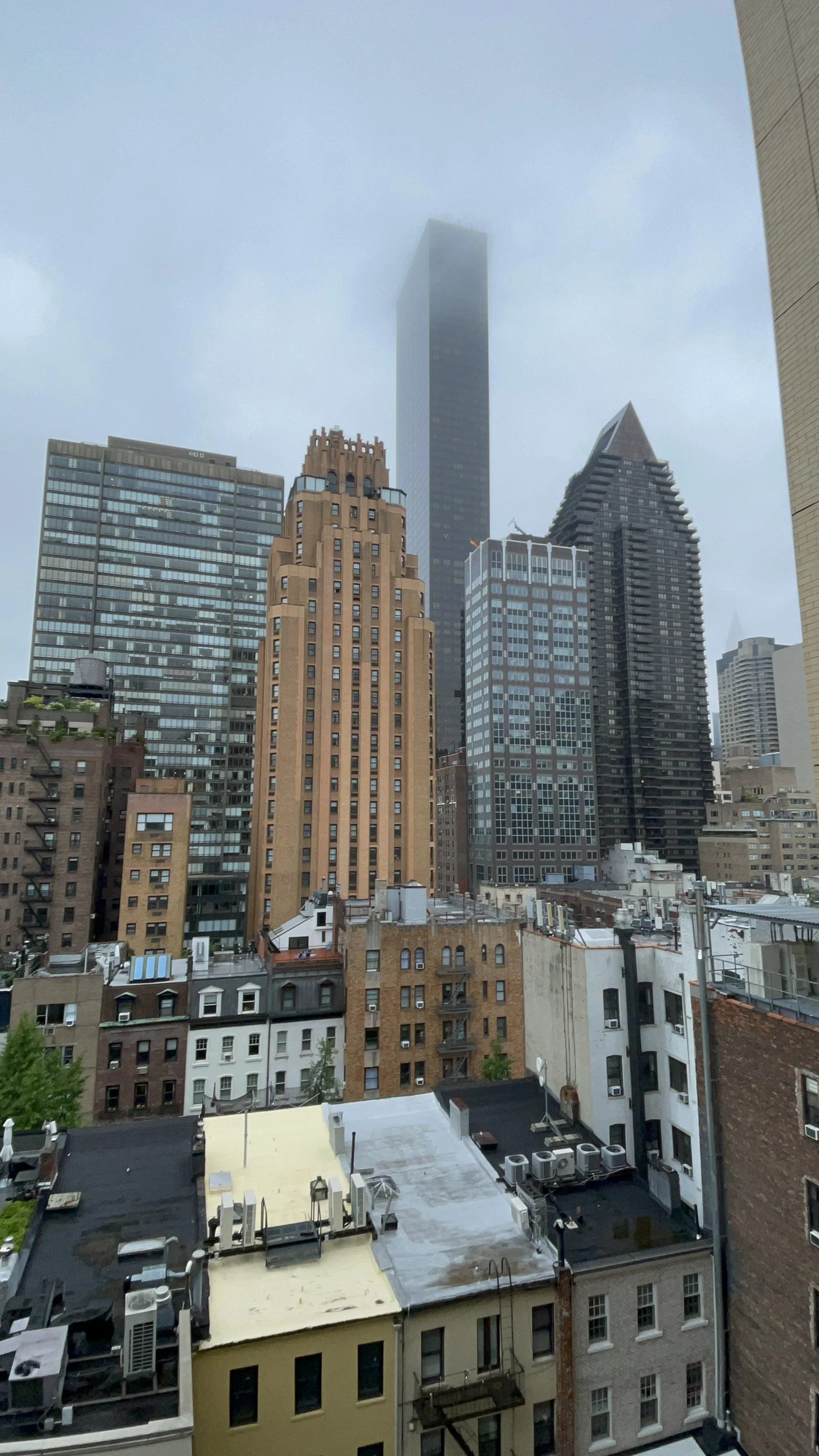 City skyline with tall skyscrapers and fog covering the top of the tallest building in the background.