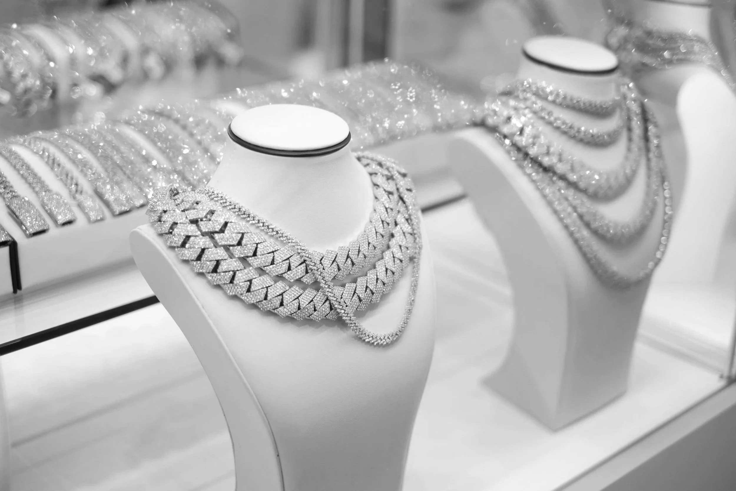 Display of jewelry including diamond necklaces and bracelets on white stands in a retail store.