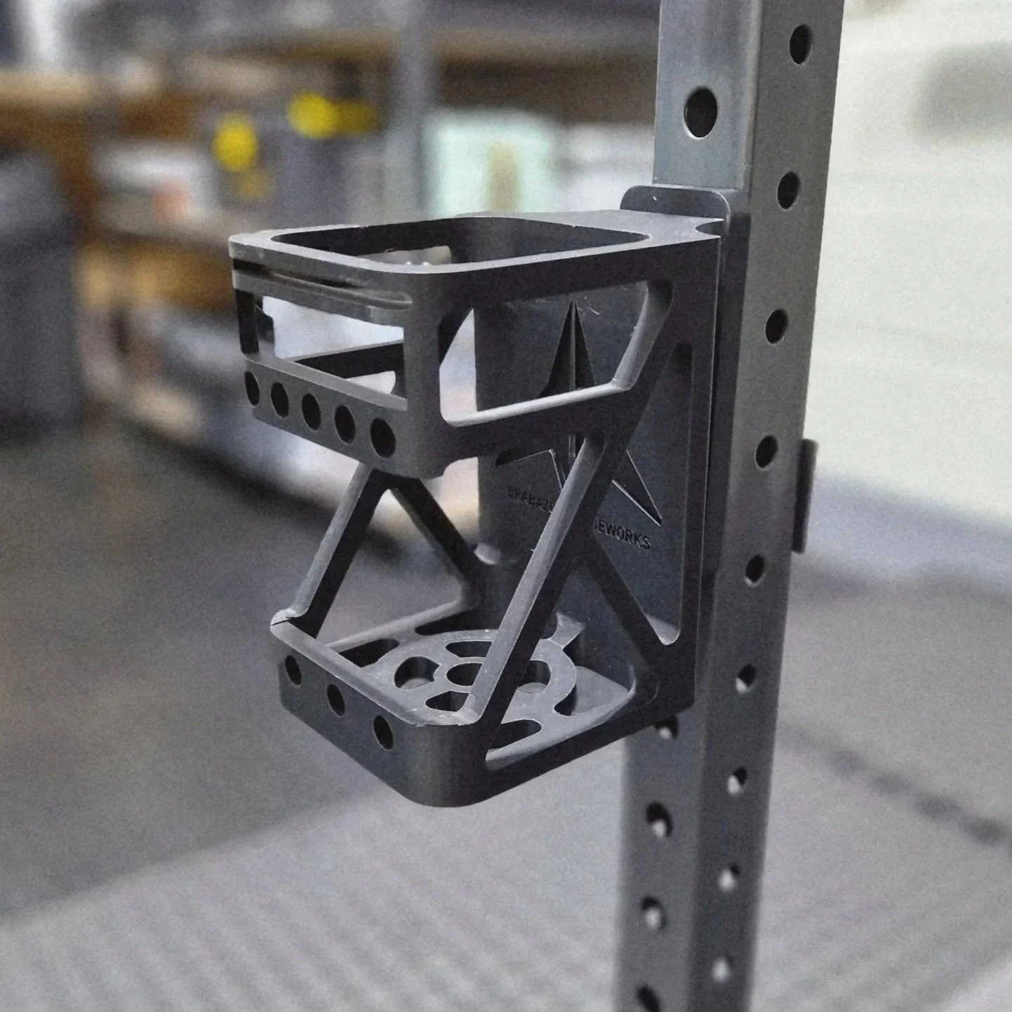 Close-up of a metallic mechanical part attached to a vertical metal strip, with a blurred background.