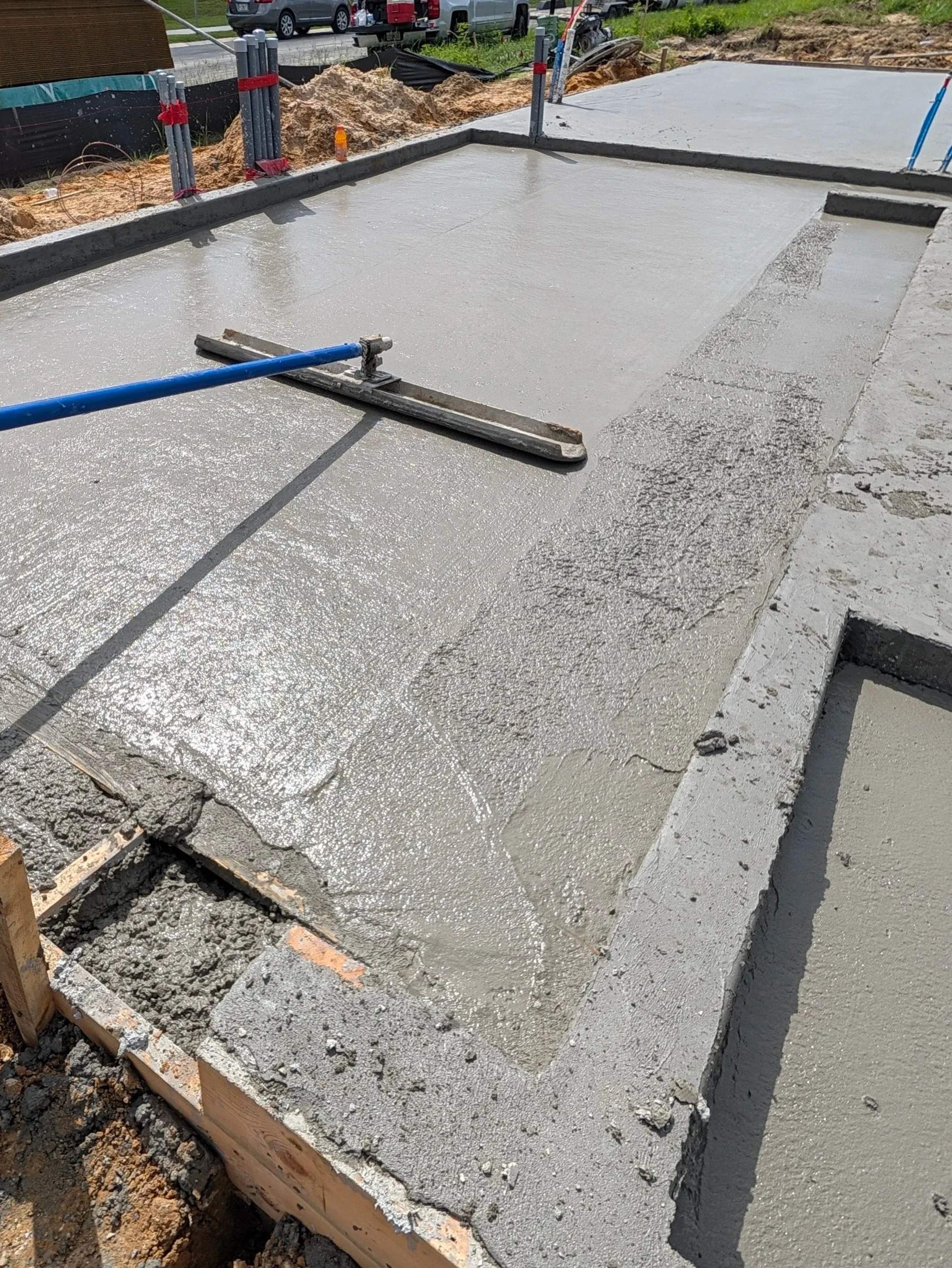 Fresh concrete slab being screeded and finished on site