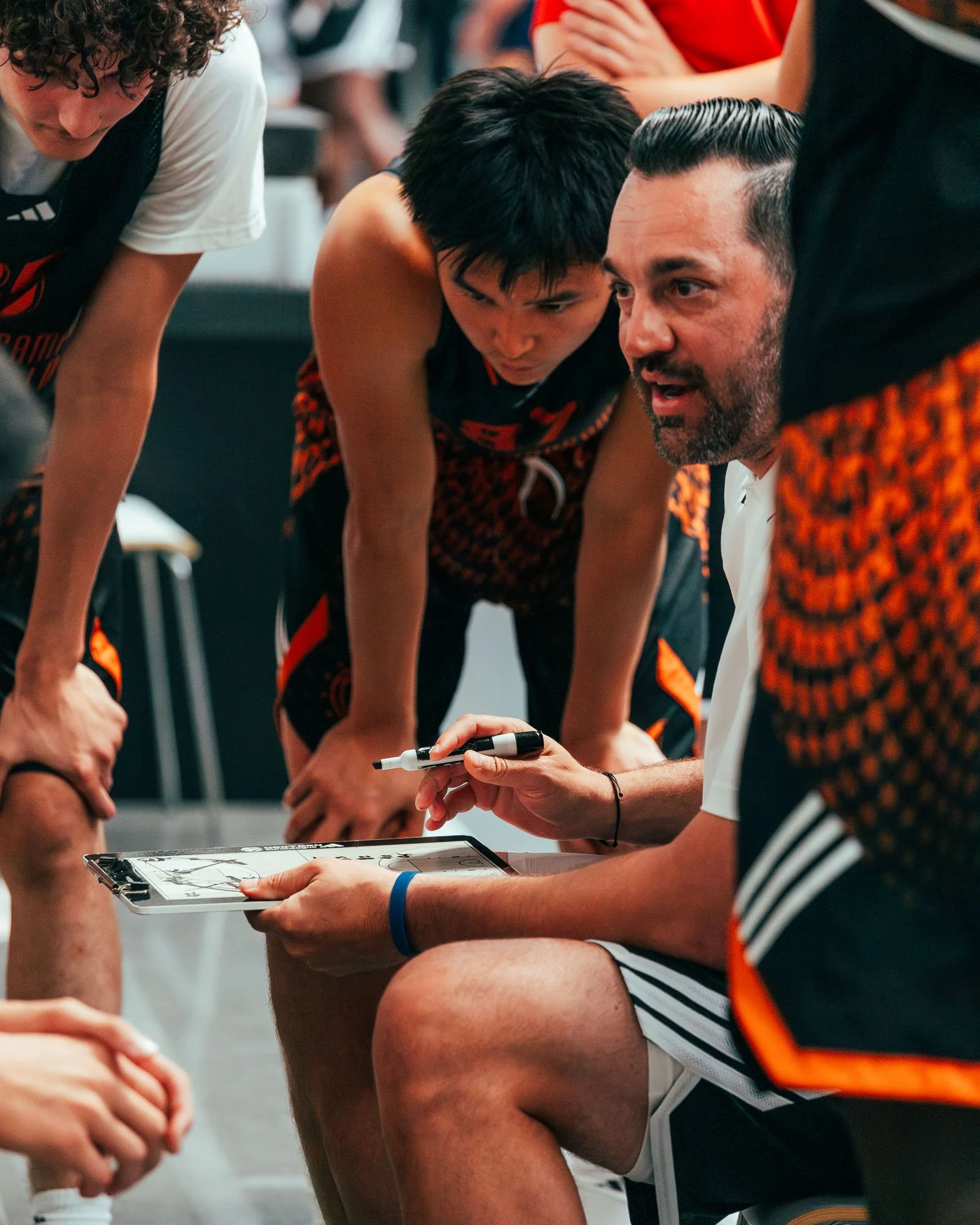 Ancora di giocatori di basket con l'allenatore che dà istruzioni durante una pausa del gioco.