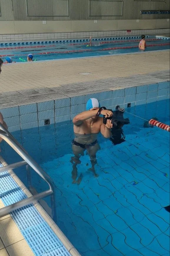 Uomo che si immerge in piscina con una macchina fotografica