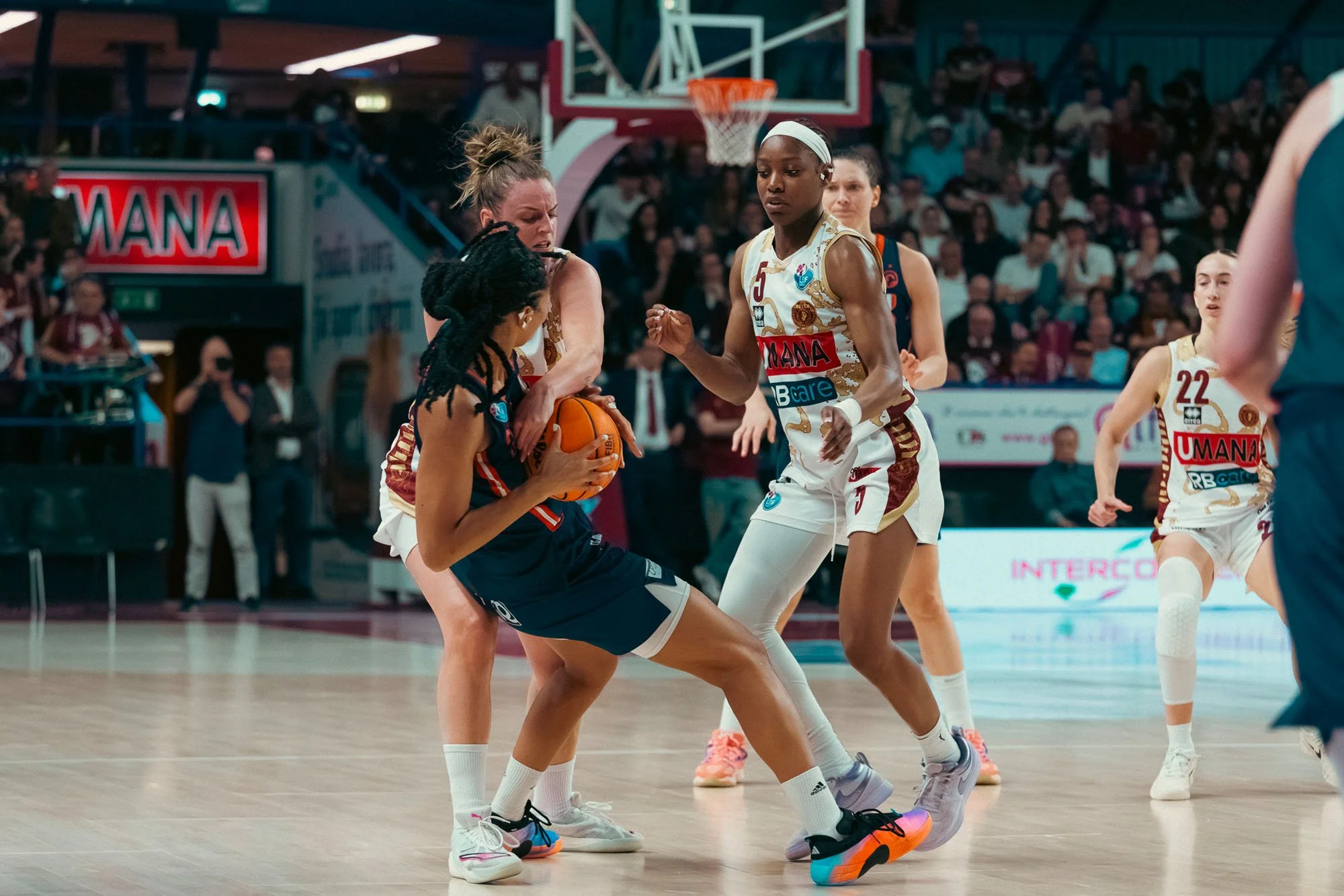 Due donne giocano a basket durante una partita, con una delle due che si contende il pallone con un'altra.