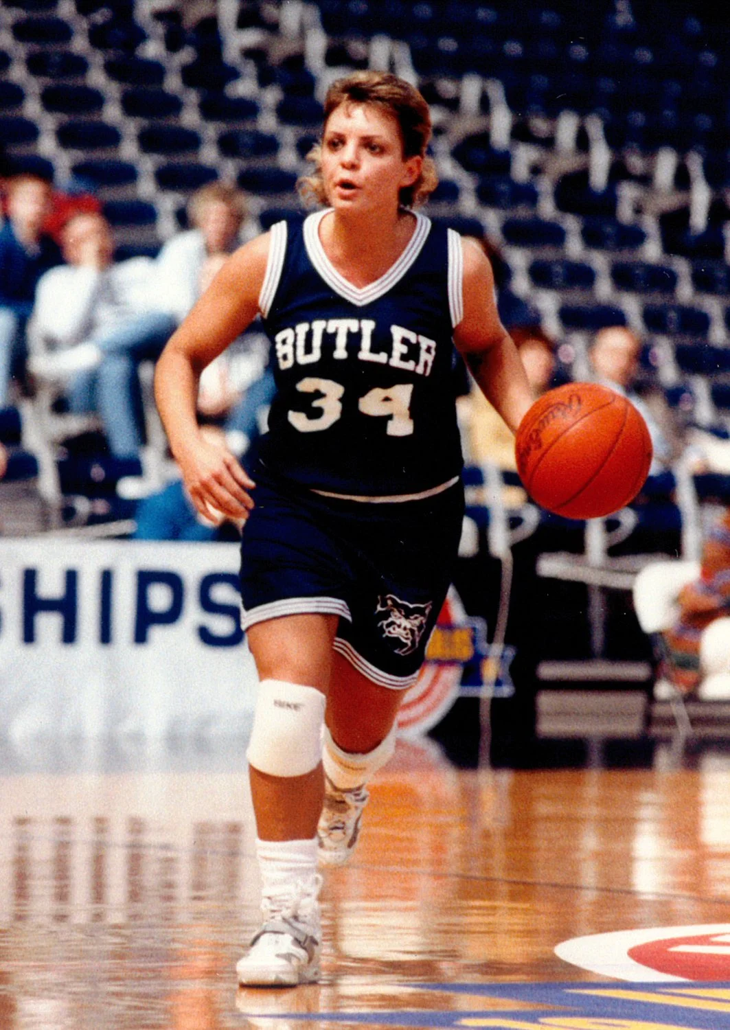 A female basketball player in a dark blue jersey with 'Butler' and the number 34, dribbling a basketball on a court.