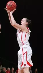 A female basketball player preparing to shoot a free throw, wearing a white jersey with red accents