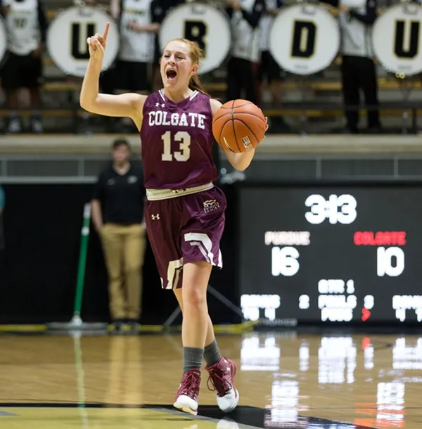 A female basketball player in a maroon uniform with 'Colgate' and the number 13, celebrating on the court with arms raised, holding a basketball. Behind her, a scoreboard shows Purdue leading 16-10 with 3:43 remaining.