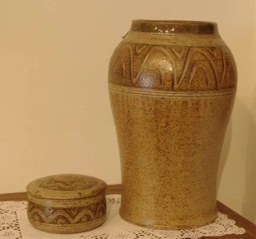 A large brown ceramic vase and a smaller round ceramic container with decorative patterns.