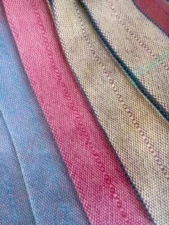 Stack of colorful woven fabric swatches in pink, blue, yellow, and beige