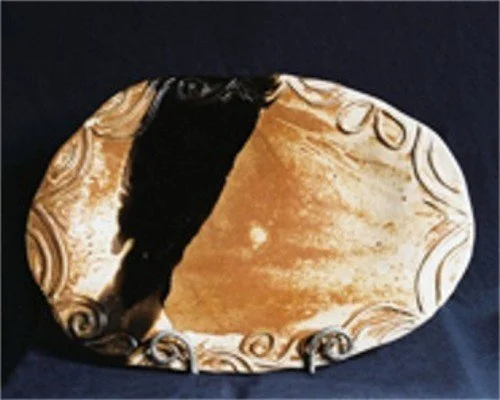 Decorative mirror with an ornate gold frame, reflecting part of a dark object and a light-colored surface.