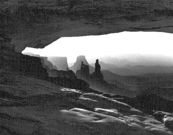 Black and white photograph of a glacier with ice formations and mountains in the background.