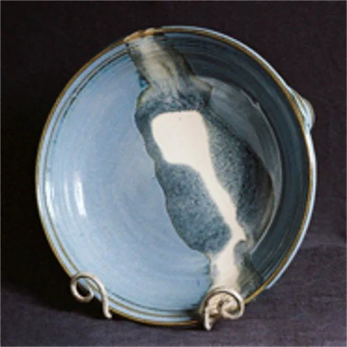 A ceramic bowl with a small jug pouring cream or milk into it.