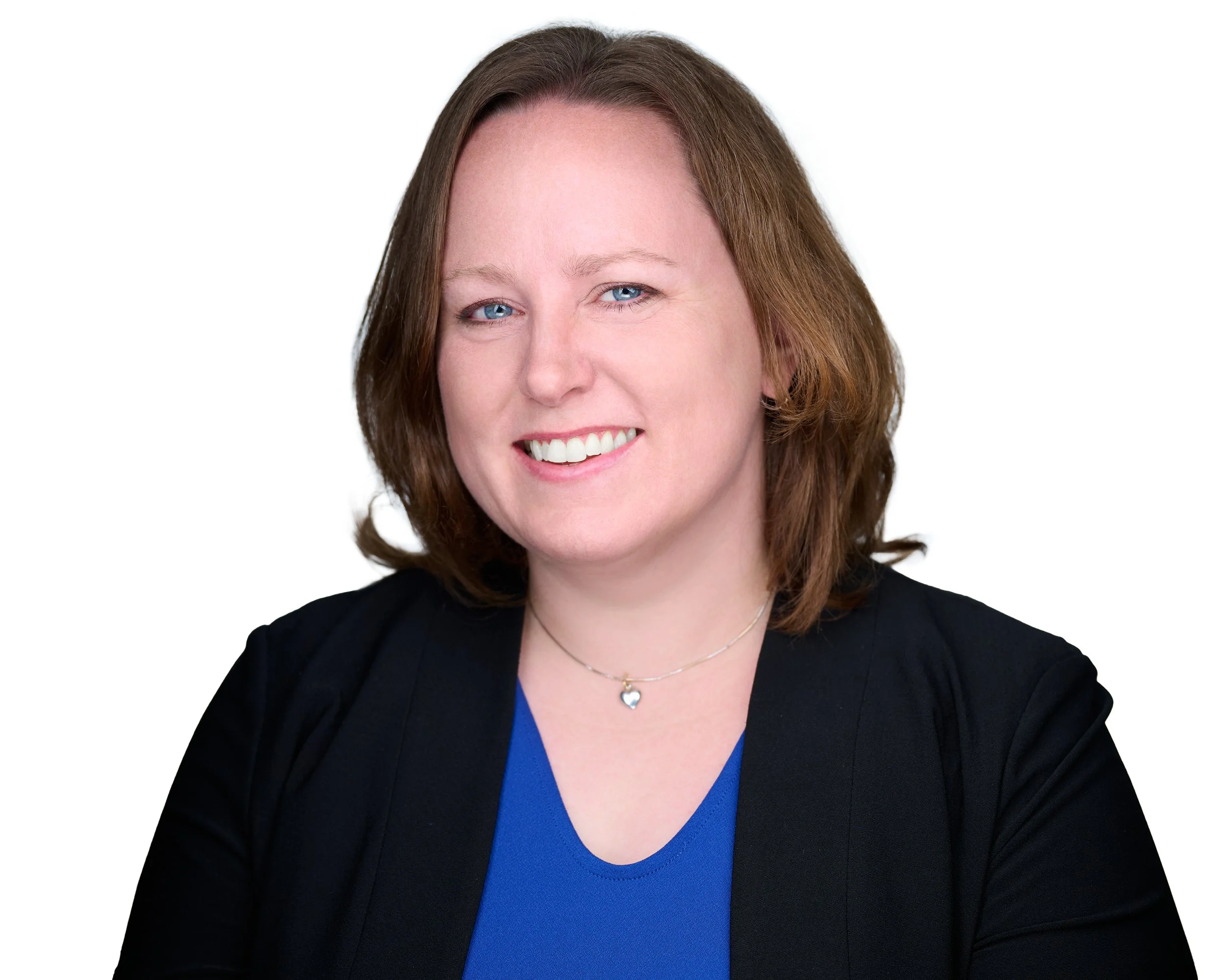 A picture of Sheila Struiksma, a smiling woman with light skin, shoulder-length reddish-brown hair, wearing a black blazer over a blue top, silver necklace with heart pendant, against a plain white background.